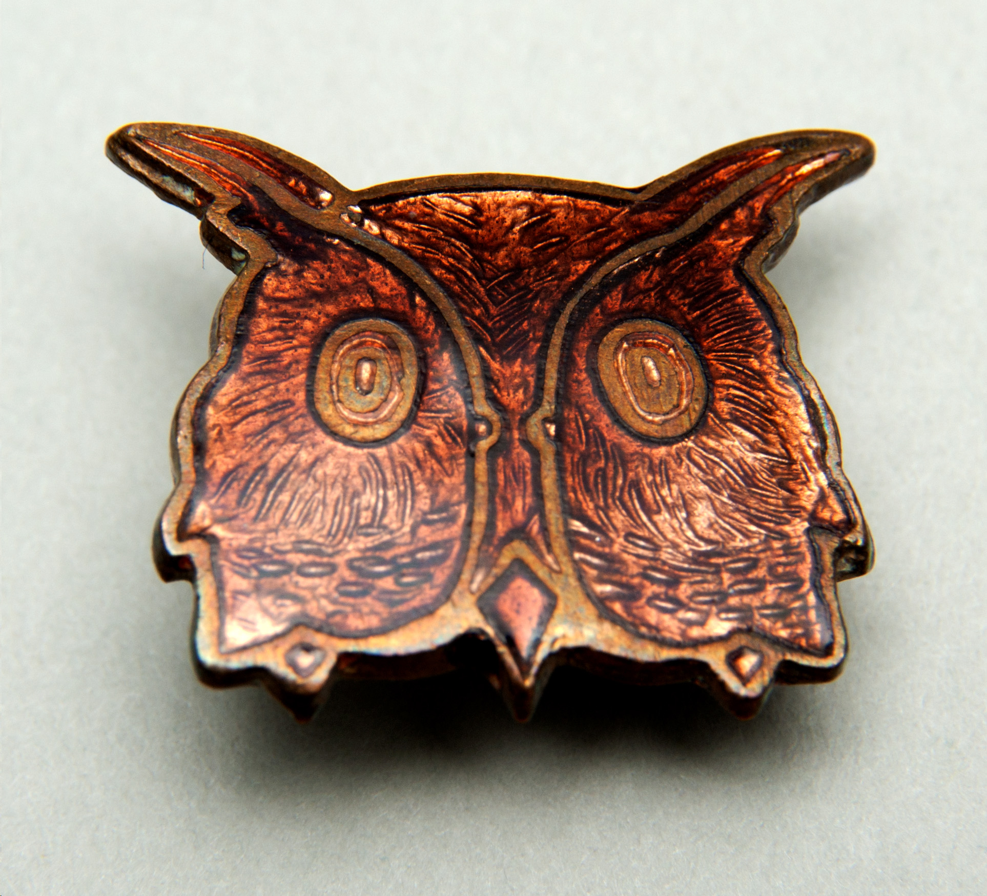 Small enamel badge in the shape of an owl's face. Enamelled in brown with feather markings