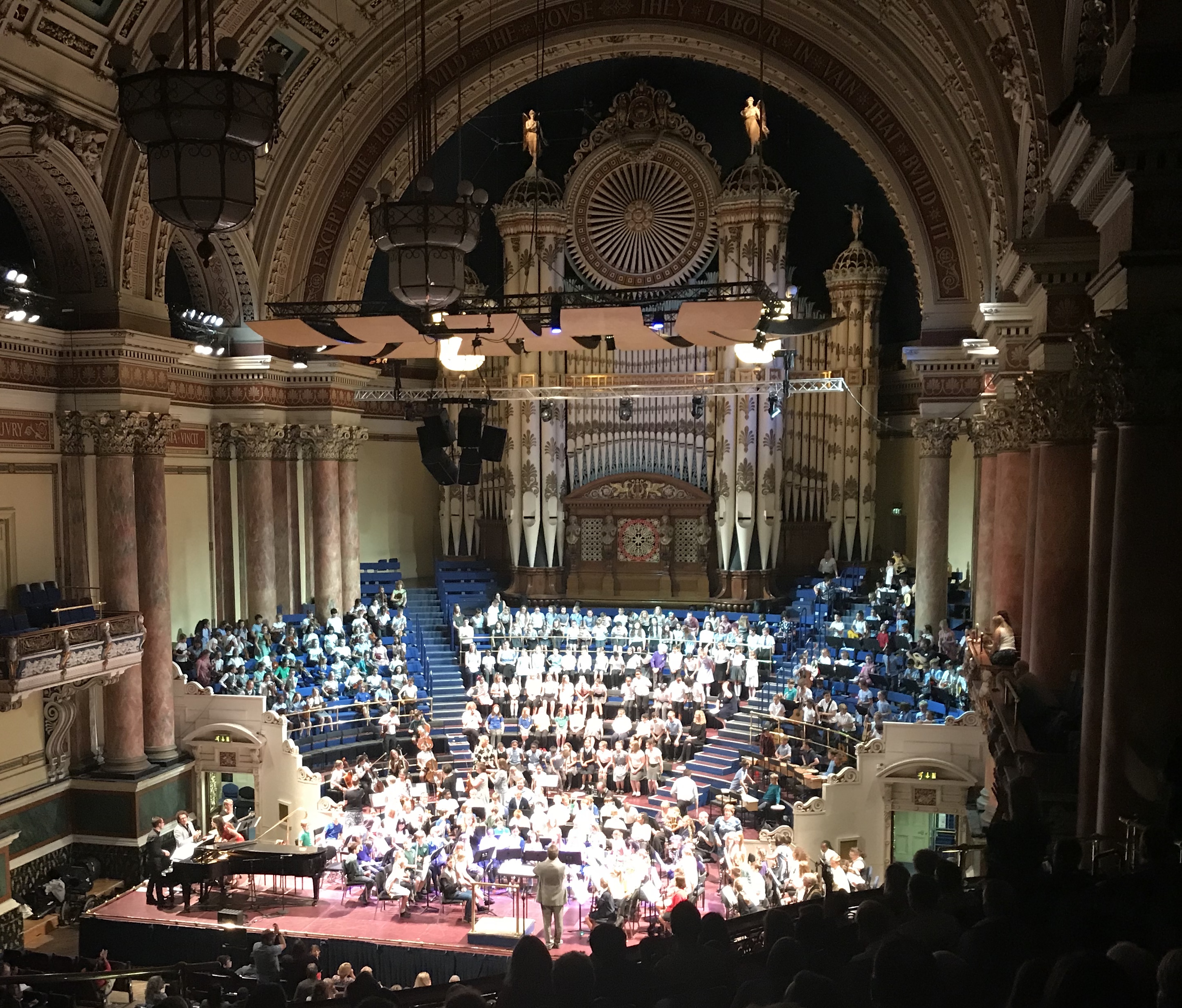 Colour photograph showing a large orchaestra and choir performing in the Leeds Town Hall