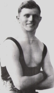 Black and white photograph showing a muscled man wearing a vest