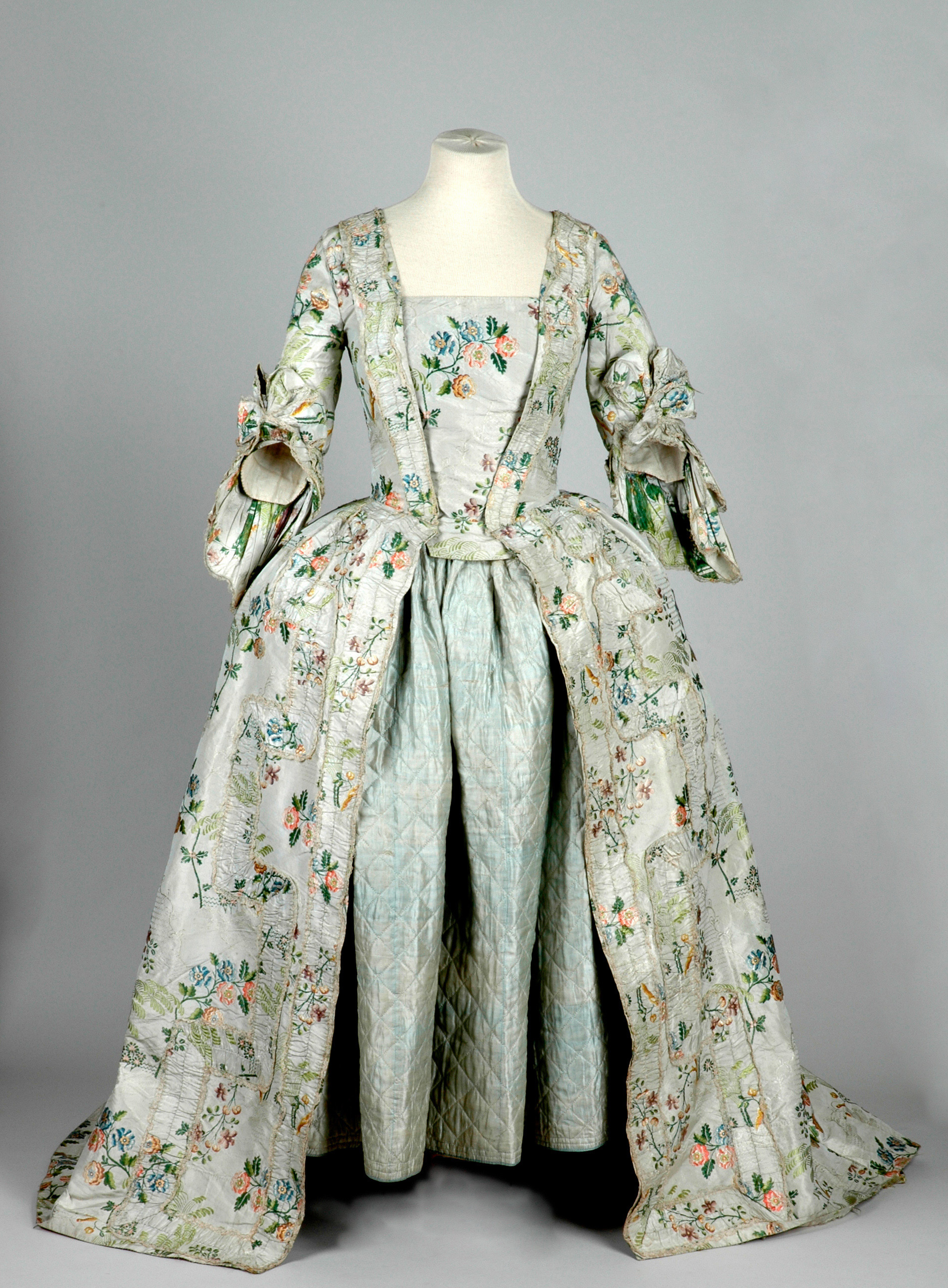 Colour photograph of a grey dress covered in hand embroidered flowers