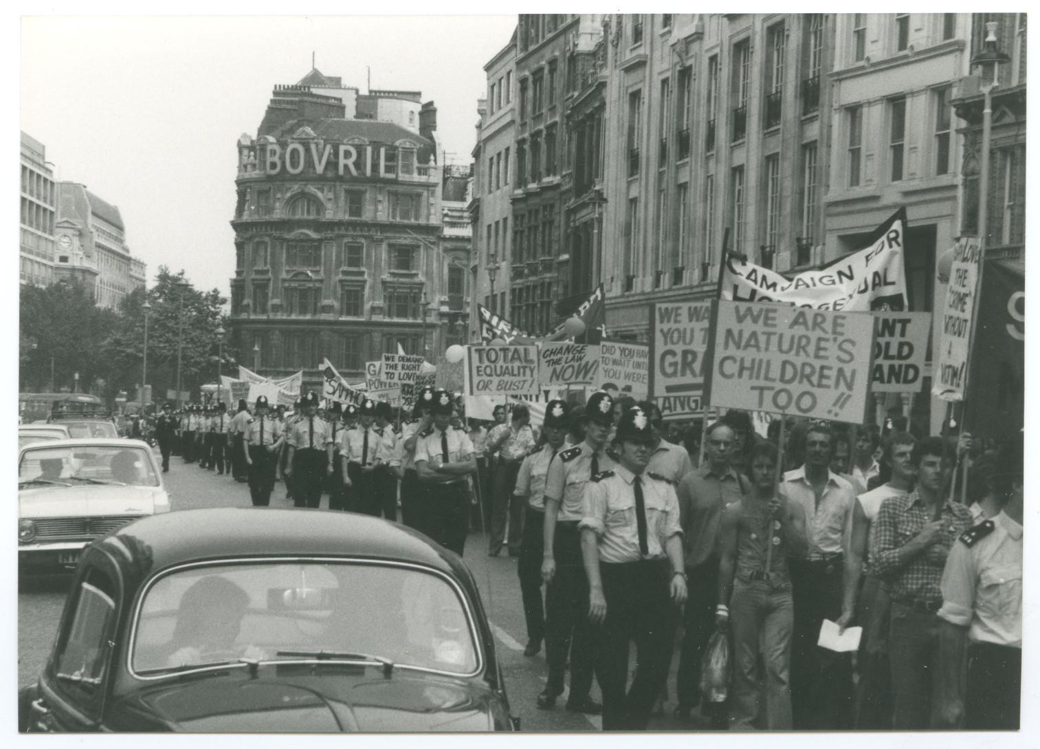 Black and white photo of marchers and police at Gay Pride march, London in 1974