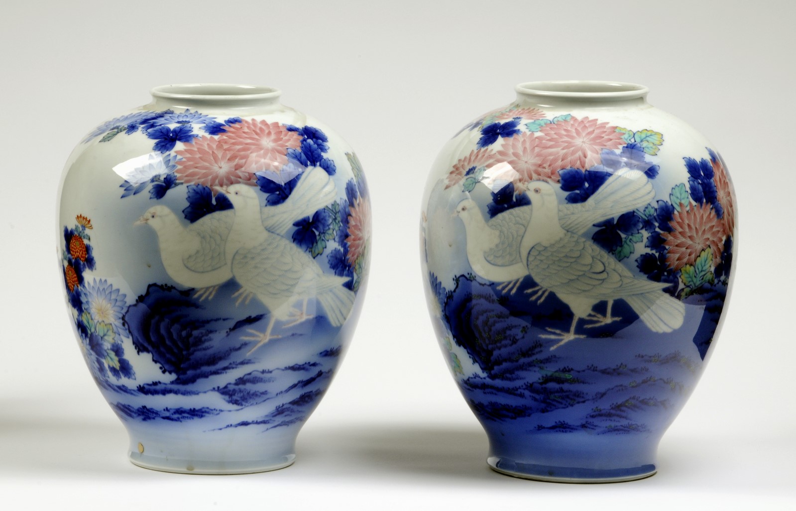 Pair of ceramic vases in white, blue and pink. Two birds on each vase with pink and blue flowers in the background