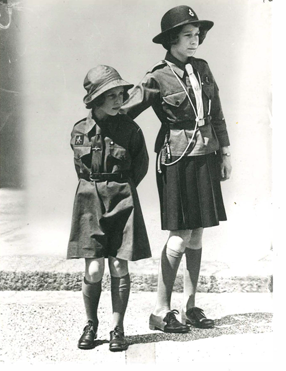 Black and white photograph showing two young girls. One in a guide uniform and one in a brownie uniform. Both are wearing hats.