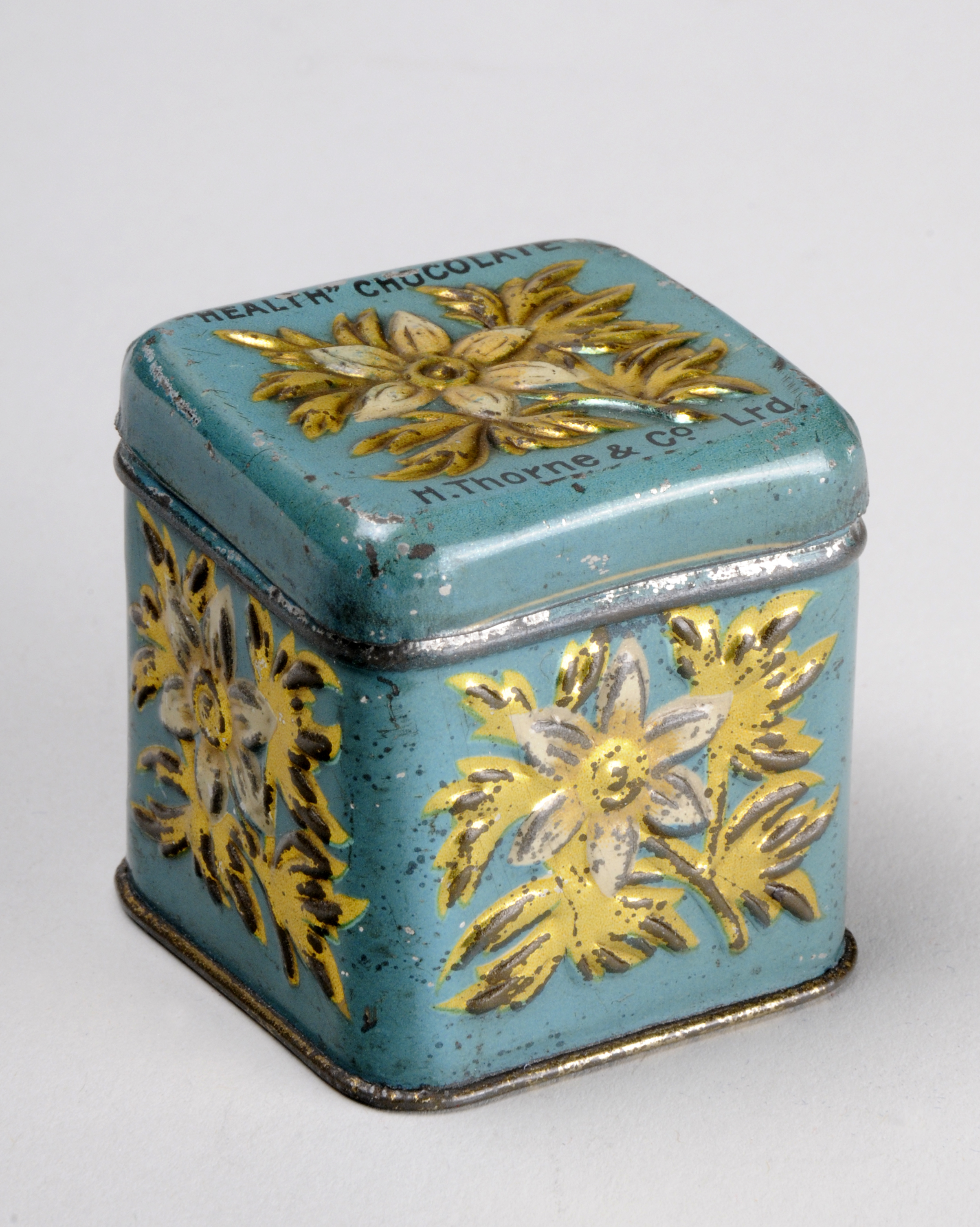 Colour photograph of a small blue tin with yellow decoration and 'Health Chocolate' written on the lid