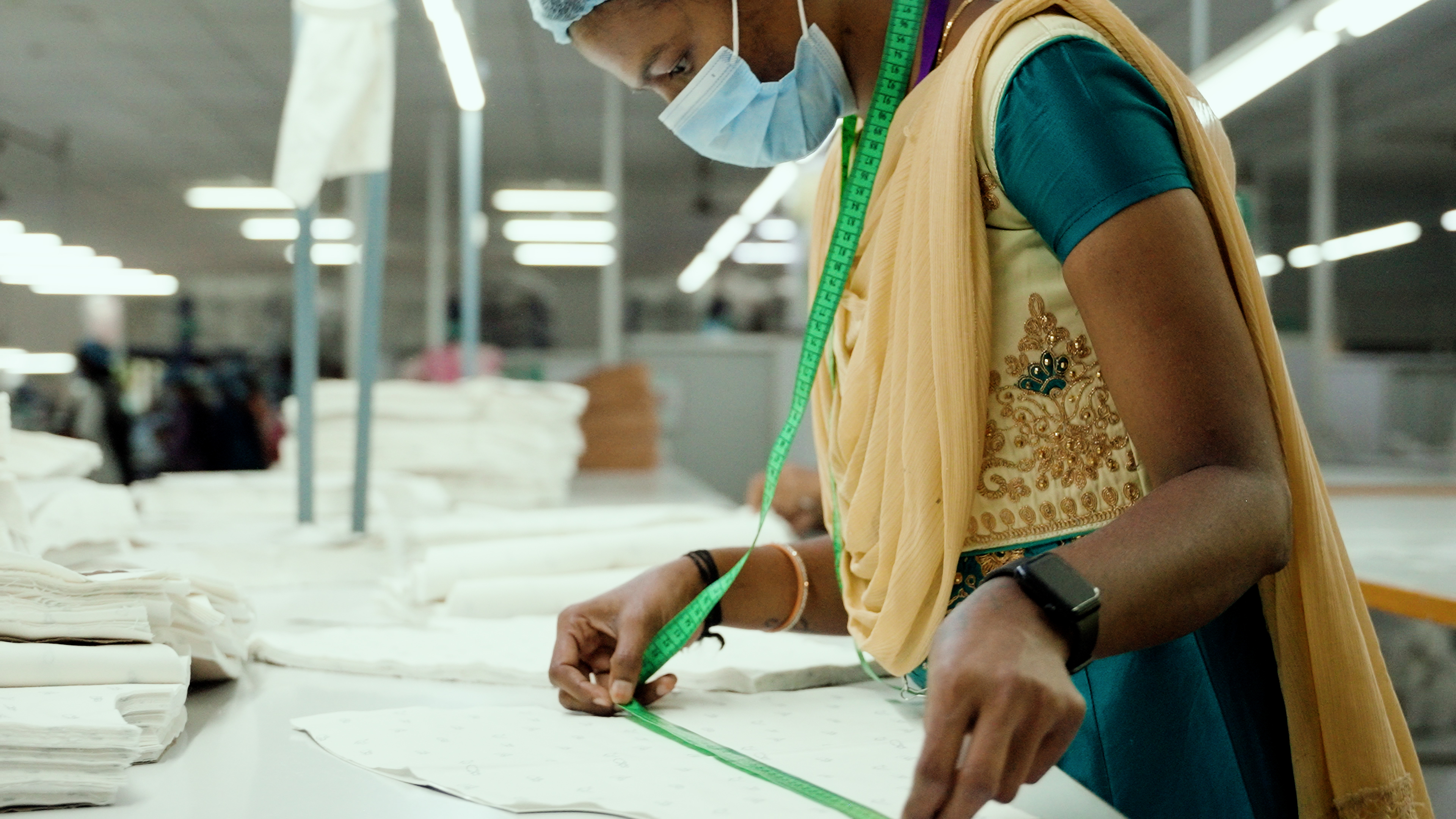 A lady measuring a piece of cloth in a factory that supplies M&S