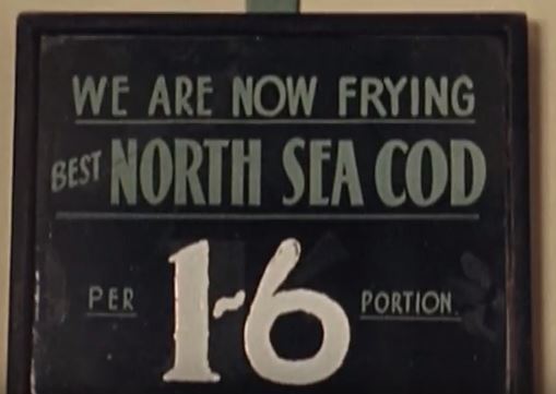 Film still showing a sign saying north sea cod for sale for 1 and 6