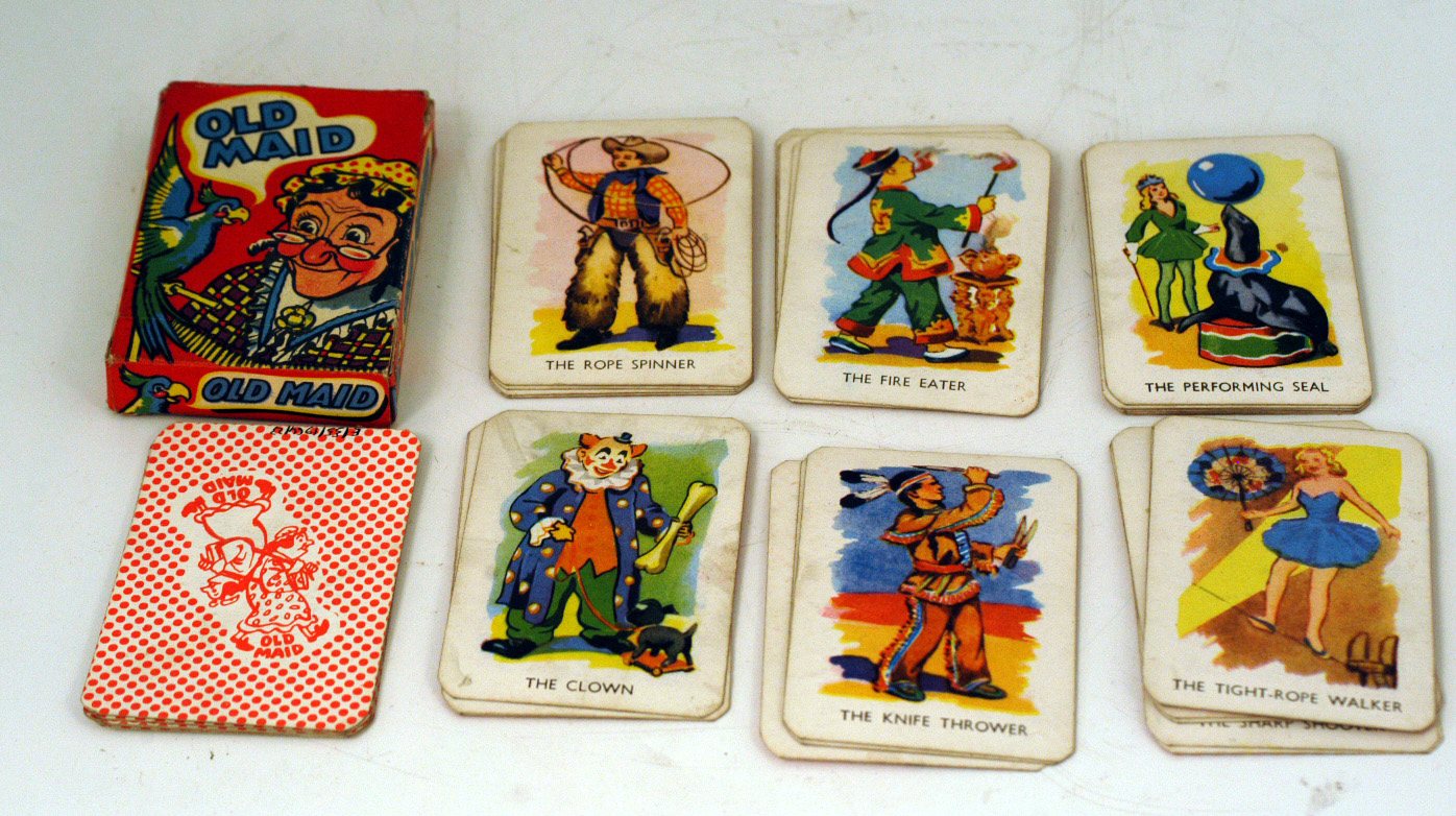 1960s card game 'Old Maid' with circus theme, including acts such as knife thrower, rope walker and performing seal.  The back of the cards show  "Old Maid" with background of dots in red on white.