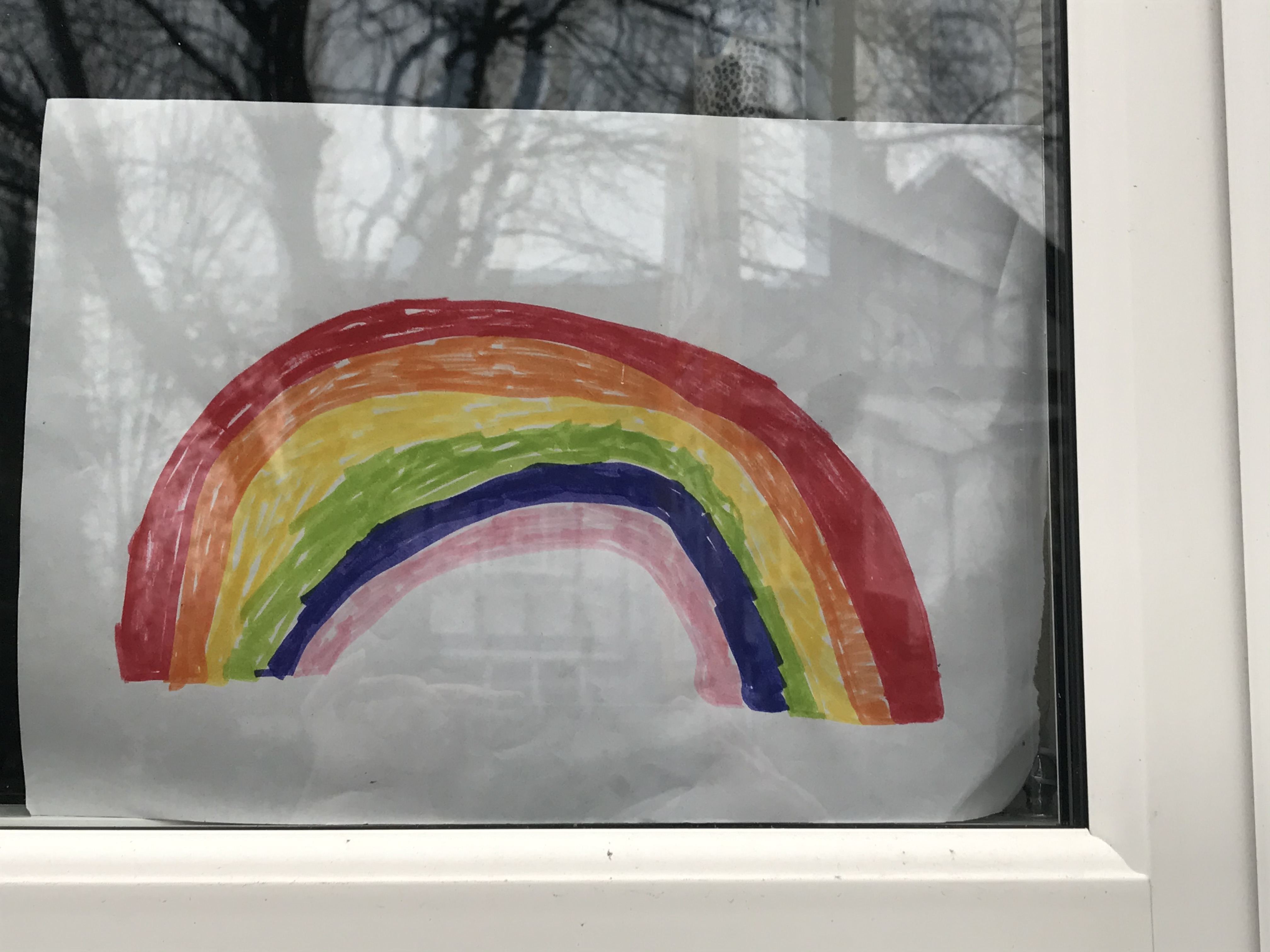 Colour photograph of a rainbow drawn in felt tip pens and put in a house window.