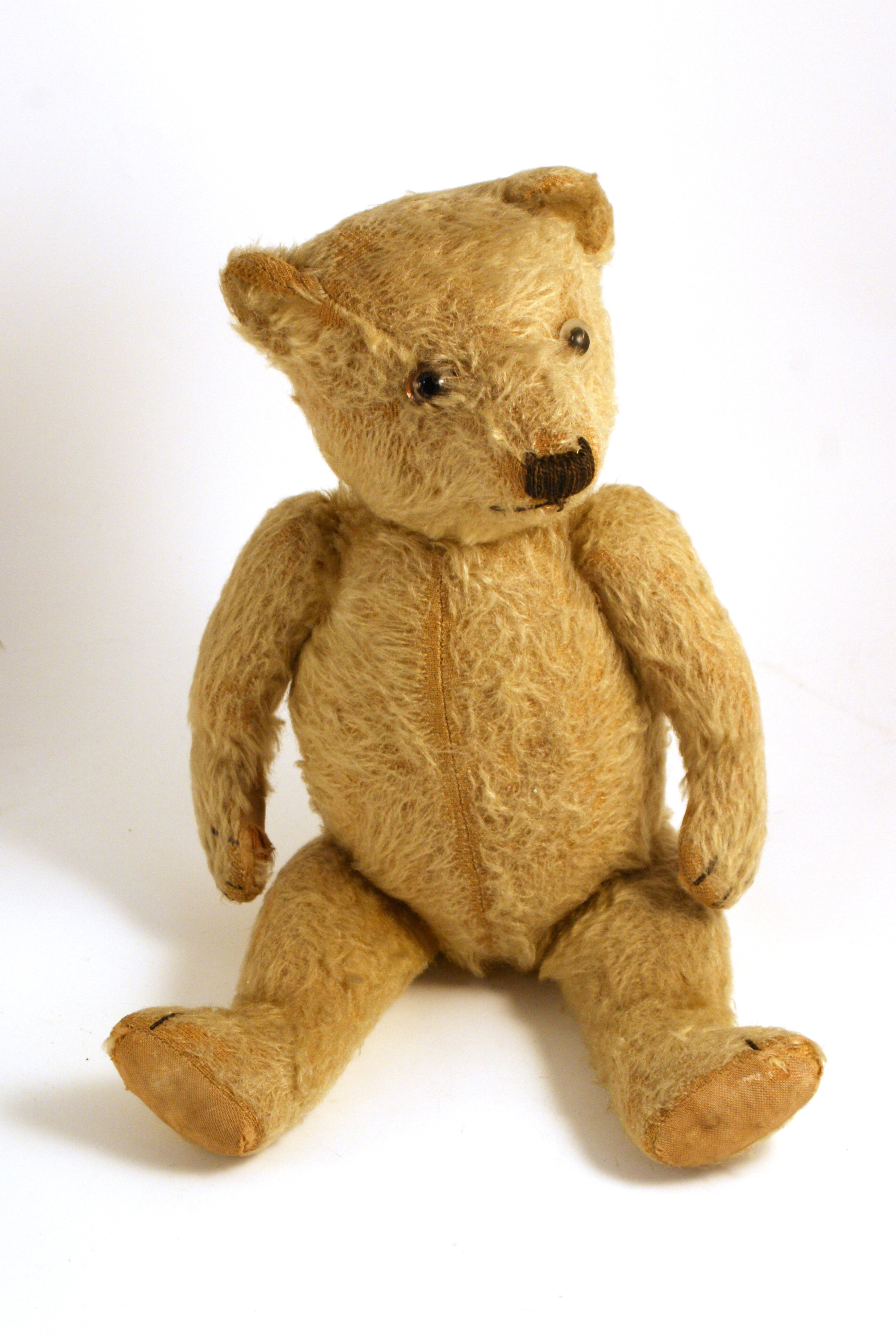 Jointed pale yellow teddy bear with seam down its belly.  It looks well loved.