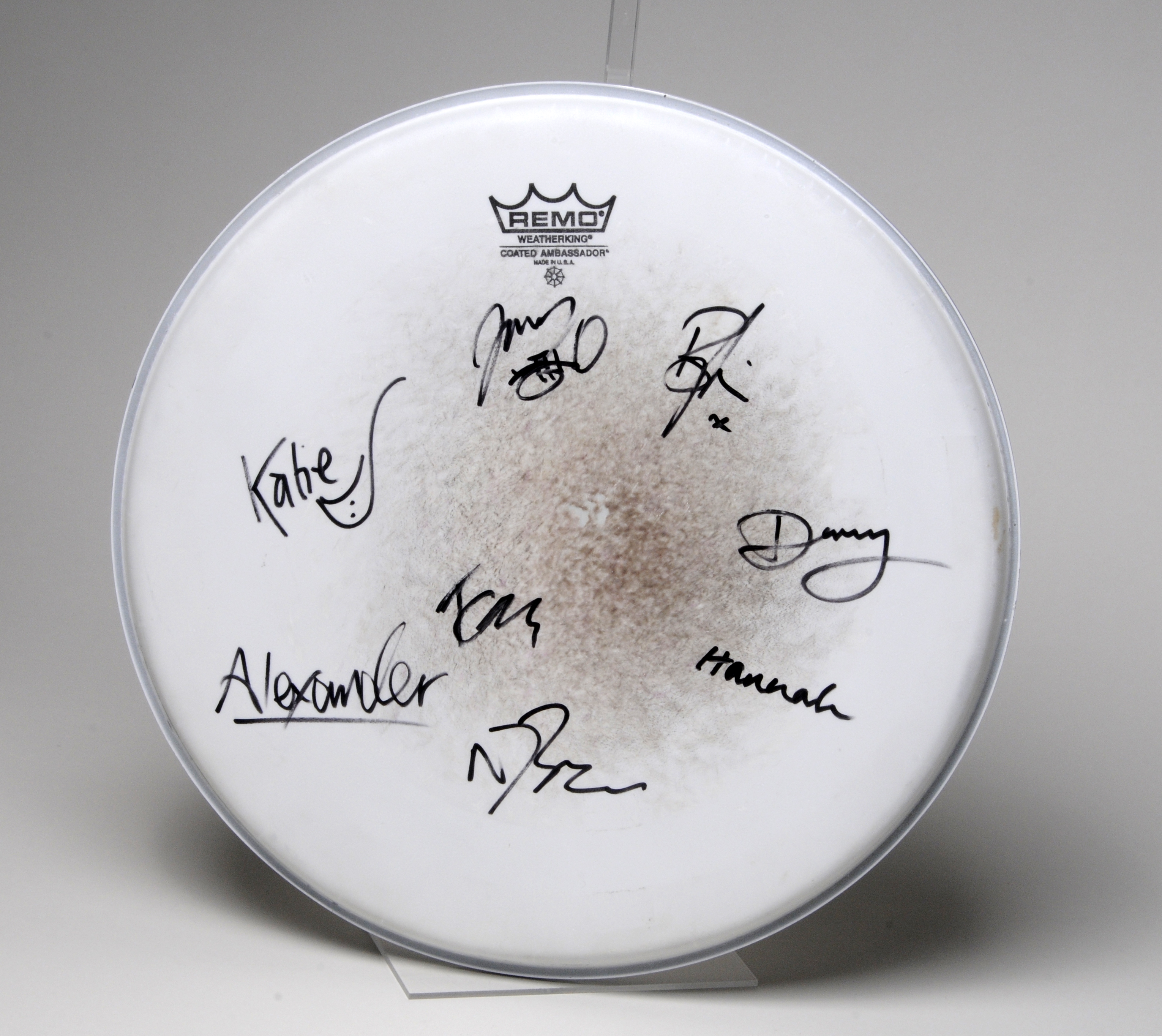 Remo brand drum head, worn from use in the centre.  Eight signatures in black felt pen have been written around it.