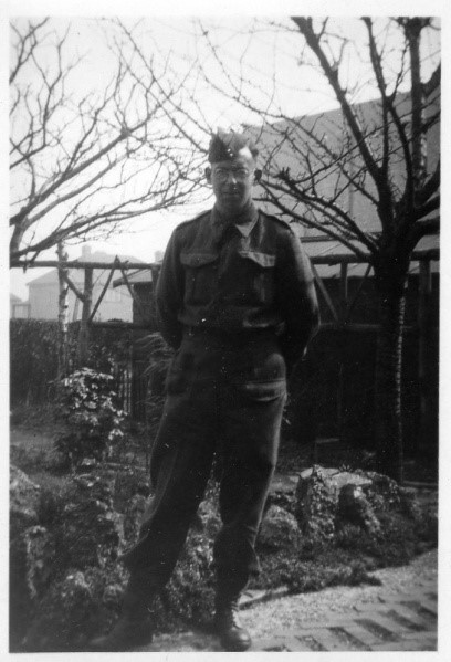 Black and white photograph of a man in military uniform standing in a garden