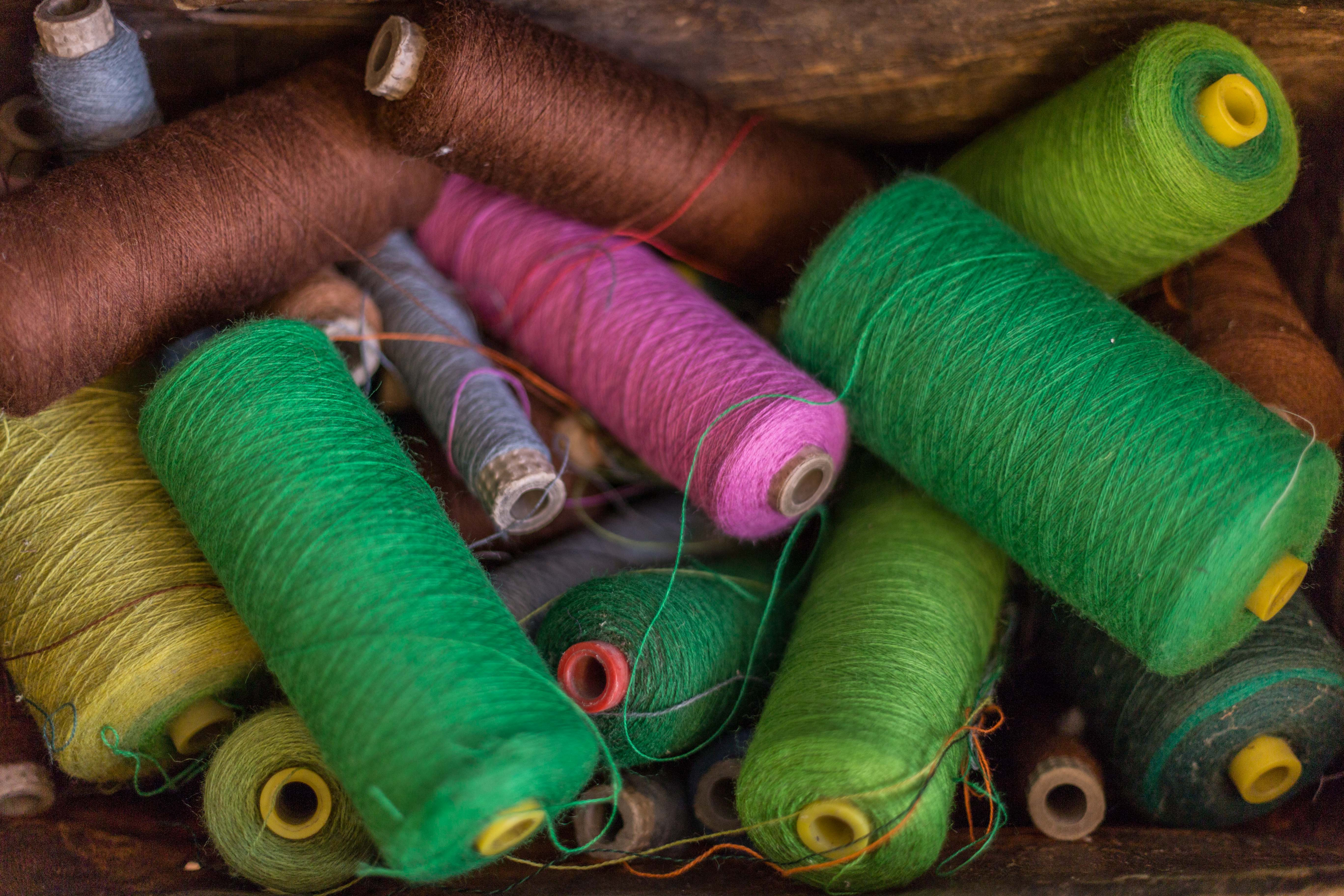 A collection of coloured yarns, including brown, greens, pink and purple