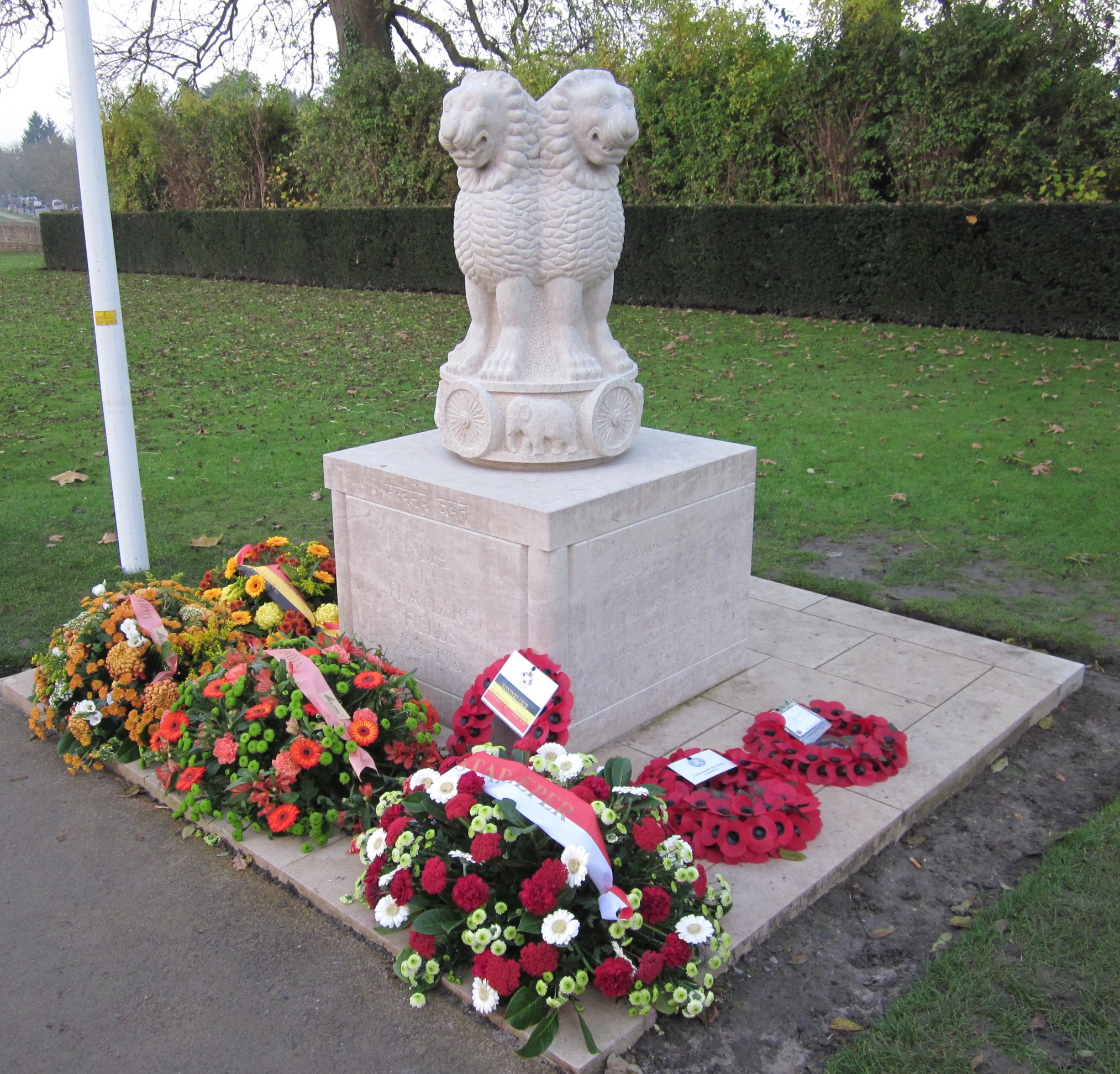 Coloured photograph showing a stone memorial. There are multiple lion type animals sculpted and they are standing on a base with wheels and elephants