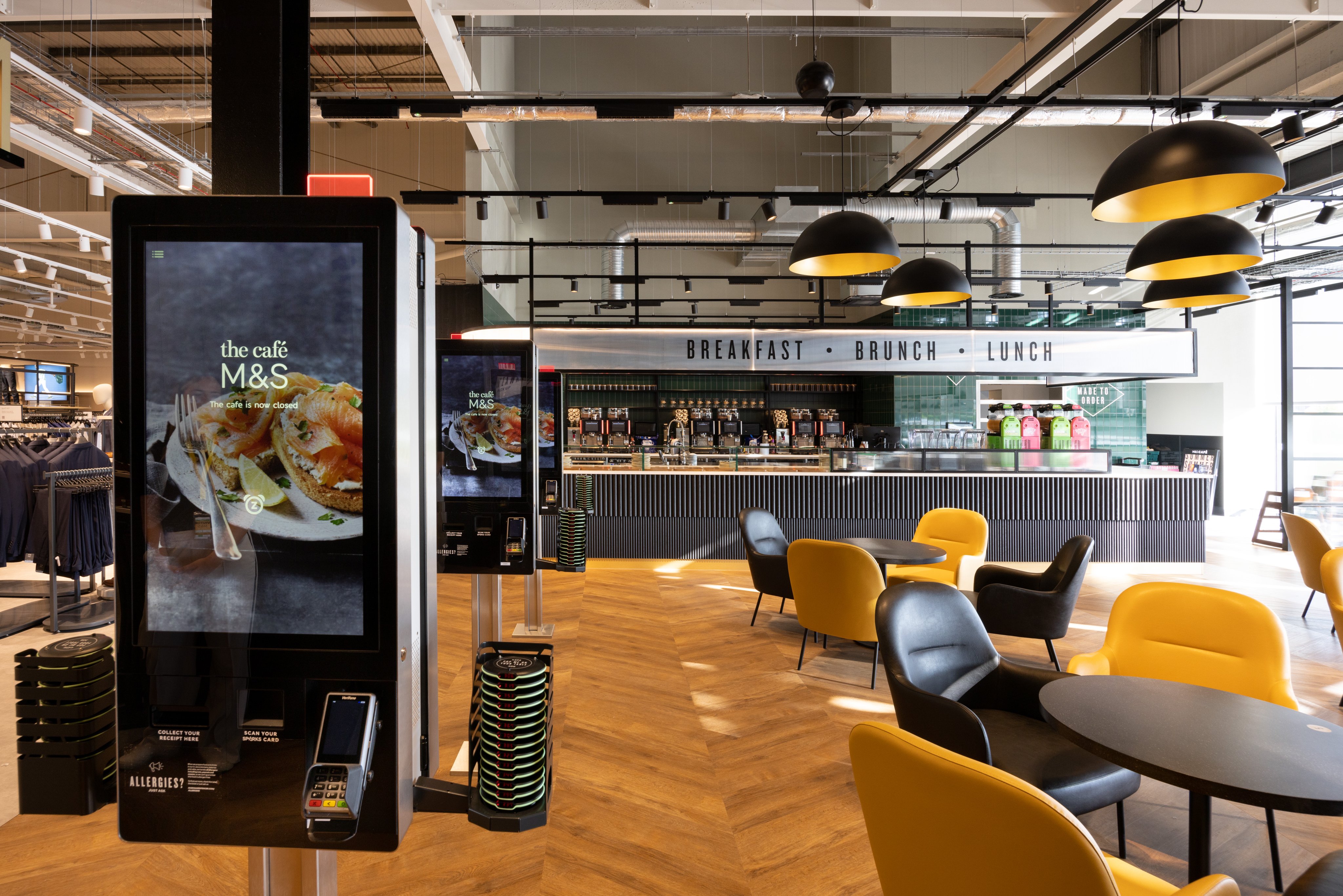 Colour photograph showing the interior of the cafe with brown and yellow comfy seats around tables.