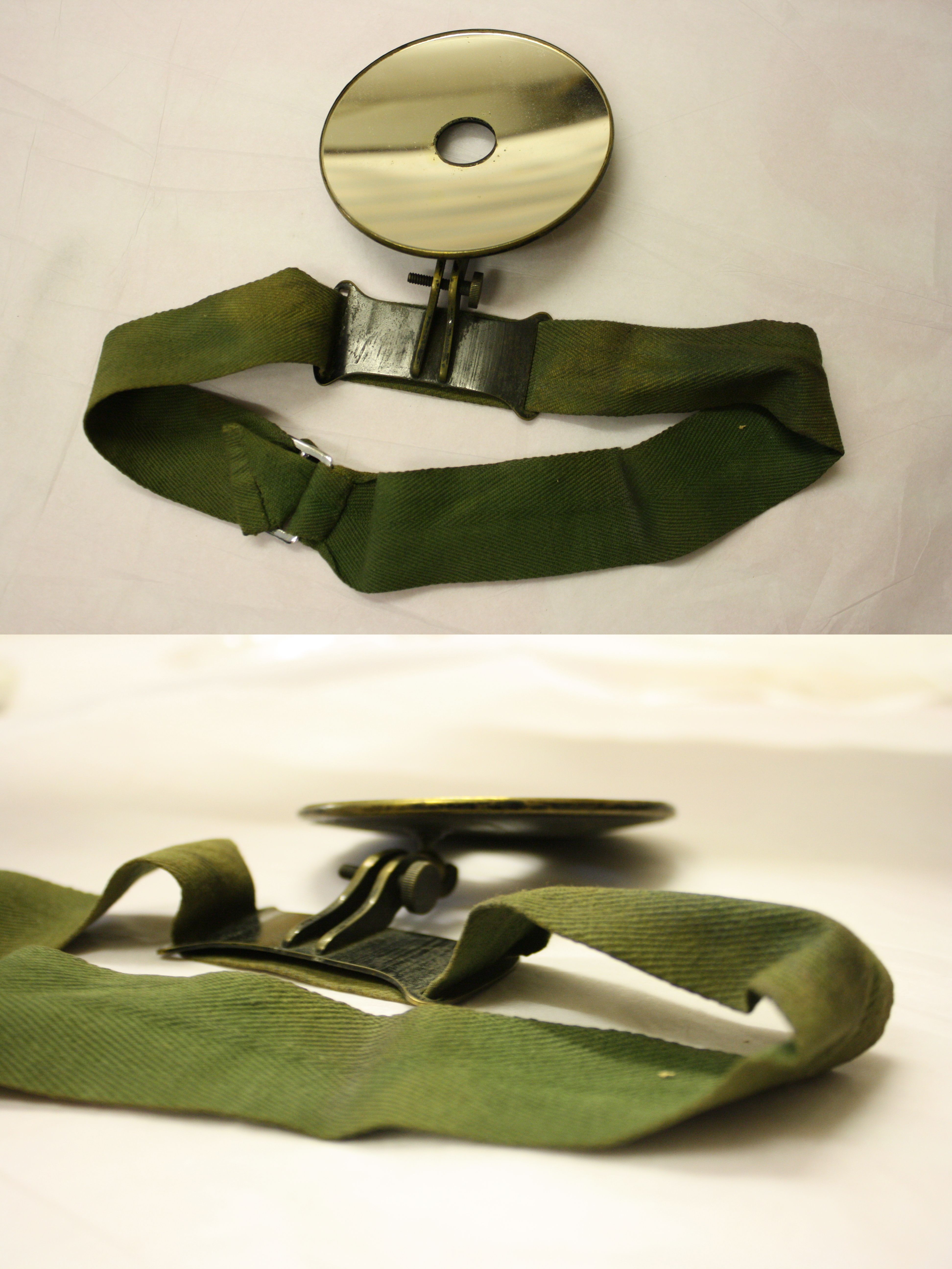 A metallic forehead mirror with a circular reflective surface is attached to an adjustable green headband.