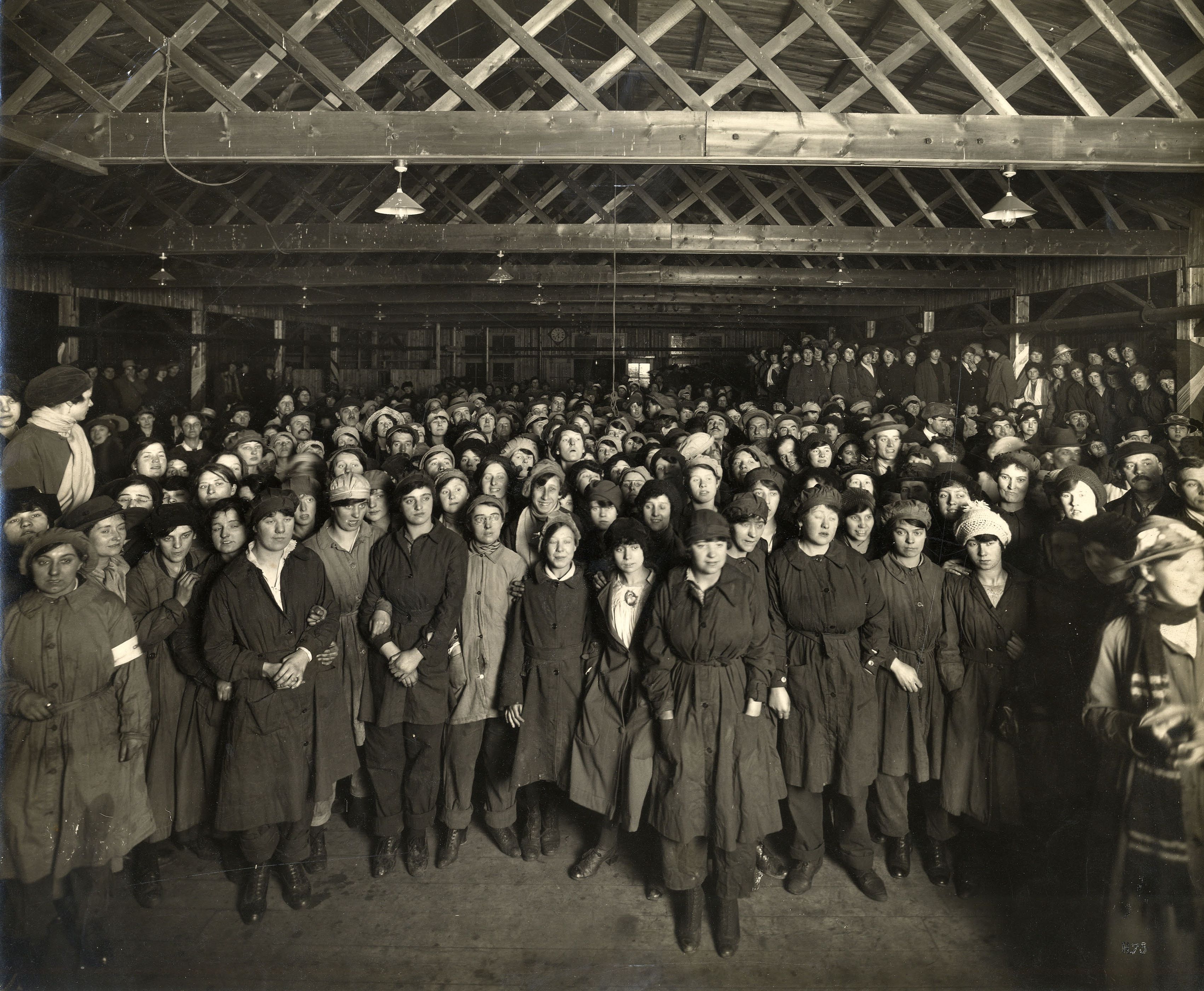 black and white photo of a crowd of people in a factory during First World War