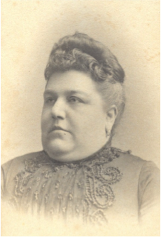 Portrait of Mary Brewer.  She is wearing a high neck dress with applique decoration around the neck and down the front.  Her hair is pinned up.
