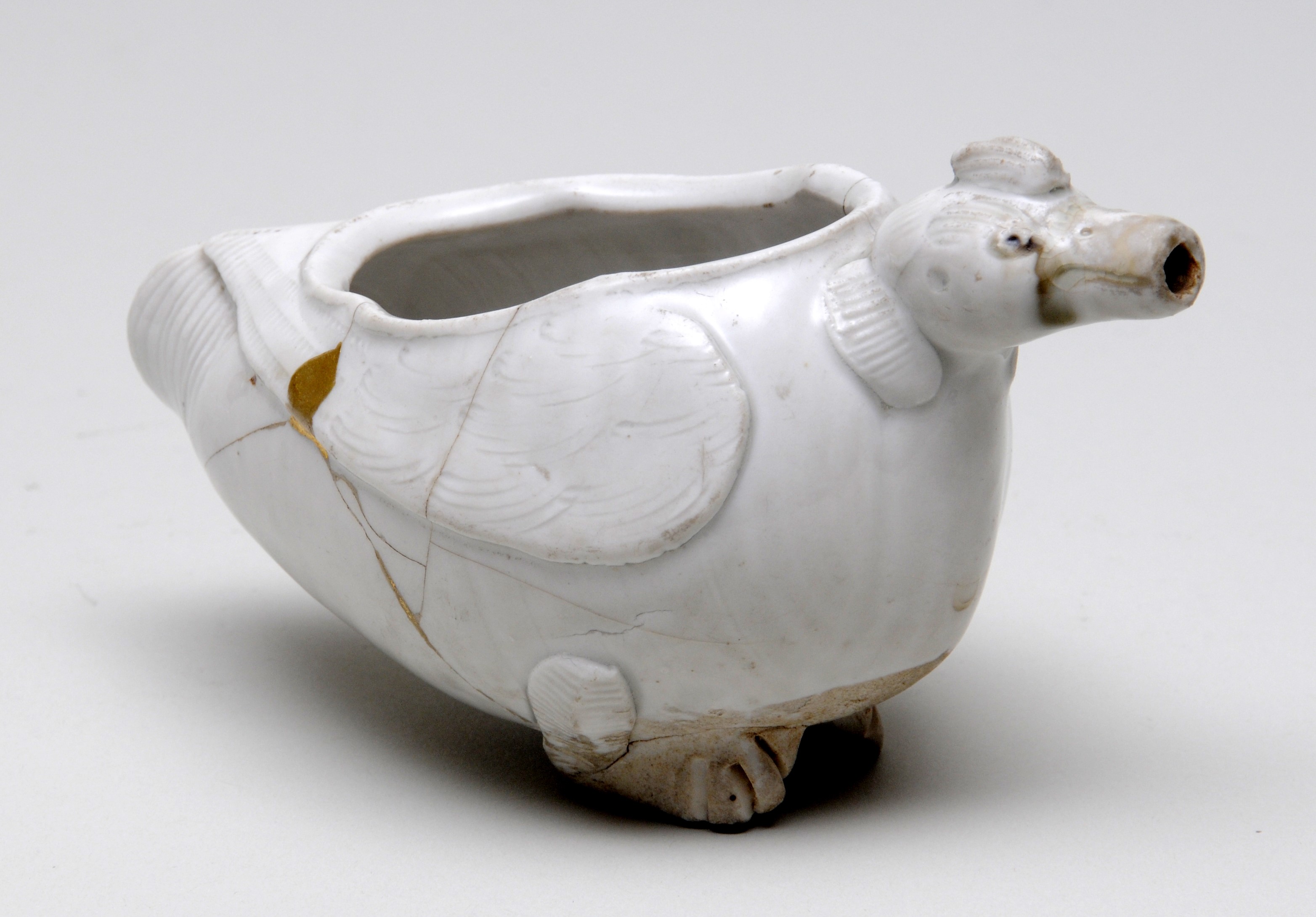 white ceramic bird shaped vessel, with a large opening in the top of the bird, and the beak acting as a spout