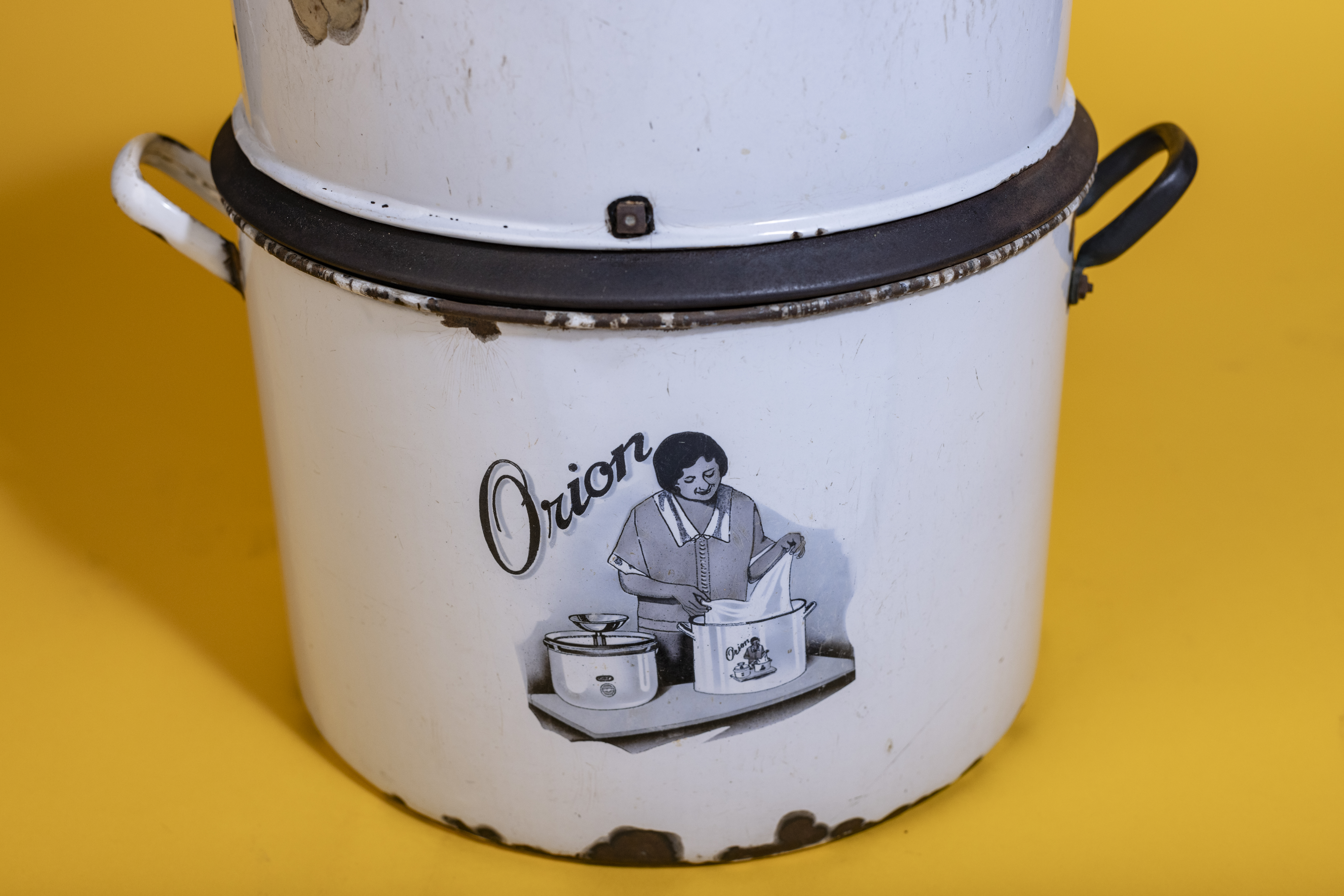 Colour photograph of a white enamelled metal tabletop washer with a drawing of a woman using it on the front.