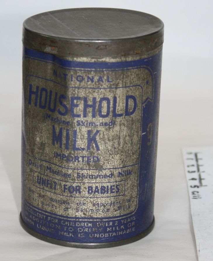 Vintage metal canister labeled "Household Milk," with faded blue and cream text. The label notes the milk is for babies. The can is worn and slightly dented.