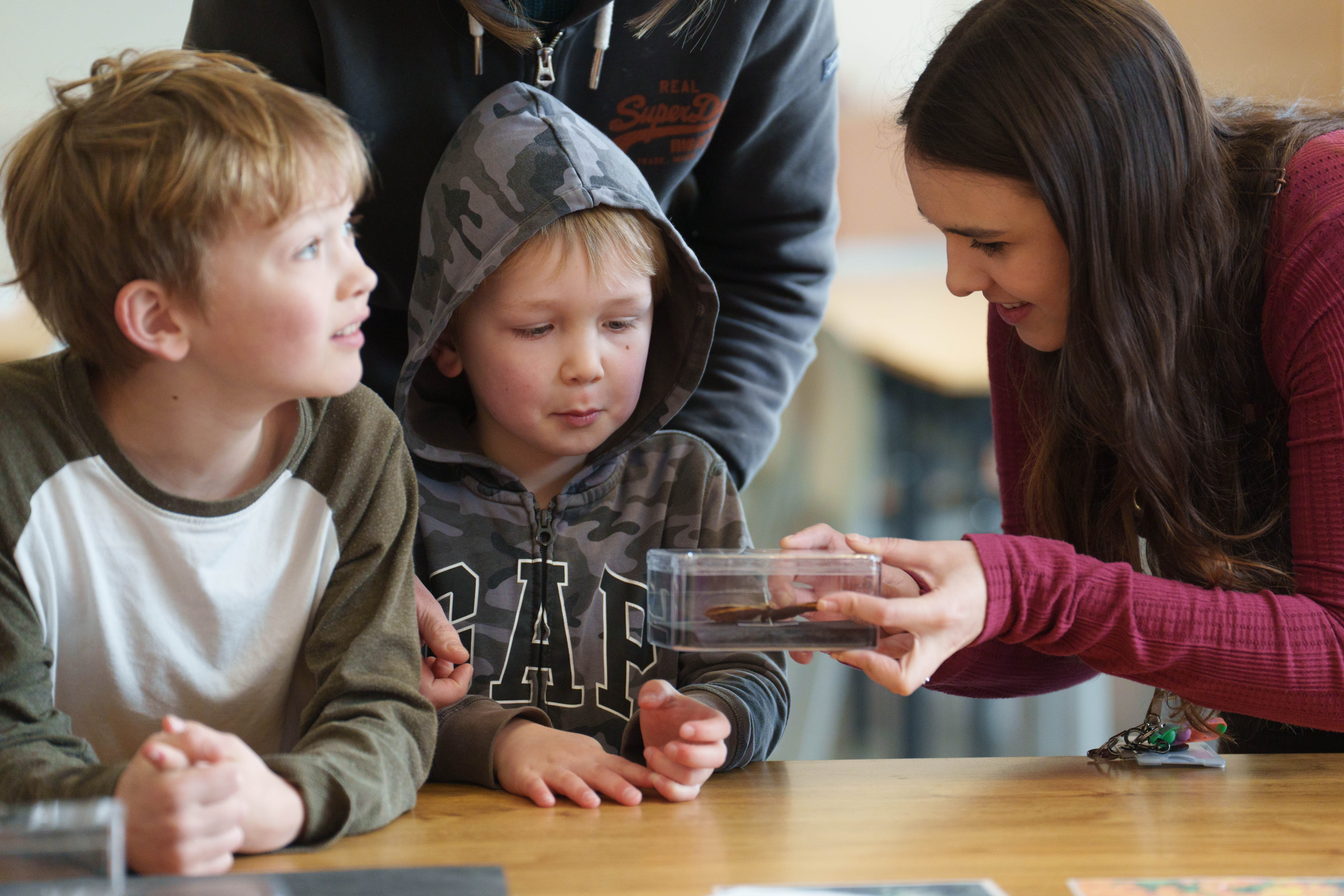 Woman holding display box whist talking to two children