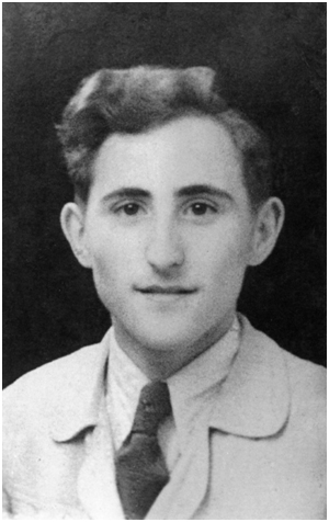 The image is a black-and-white photograph of a young man with short, neatly combed hair. He has a slight smile and wears a light-coloured jacket over a buttoned shirt with a tie. he man has a calm expression and looks directly at the camera.