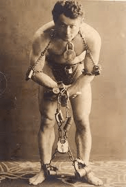 Harry Houdini posing with chains and padlocks wrapped around his body