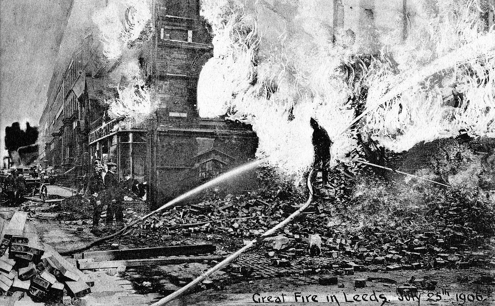 Postcard showing firemen tackling a huge blazing building with water hoses