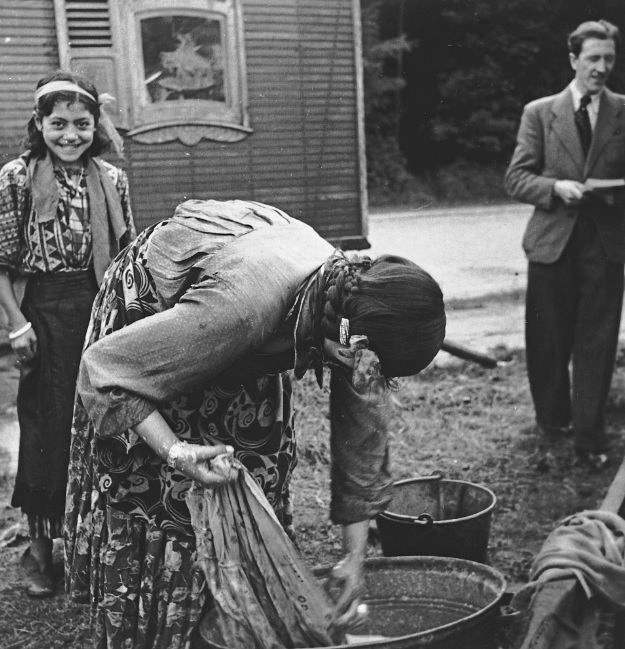 Photo of Roma Family in 1930s Europe, a woman is washing clothes in a metal tub
