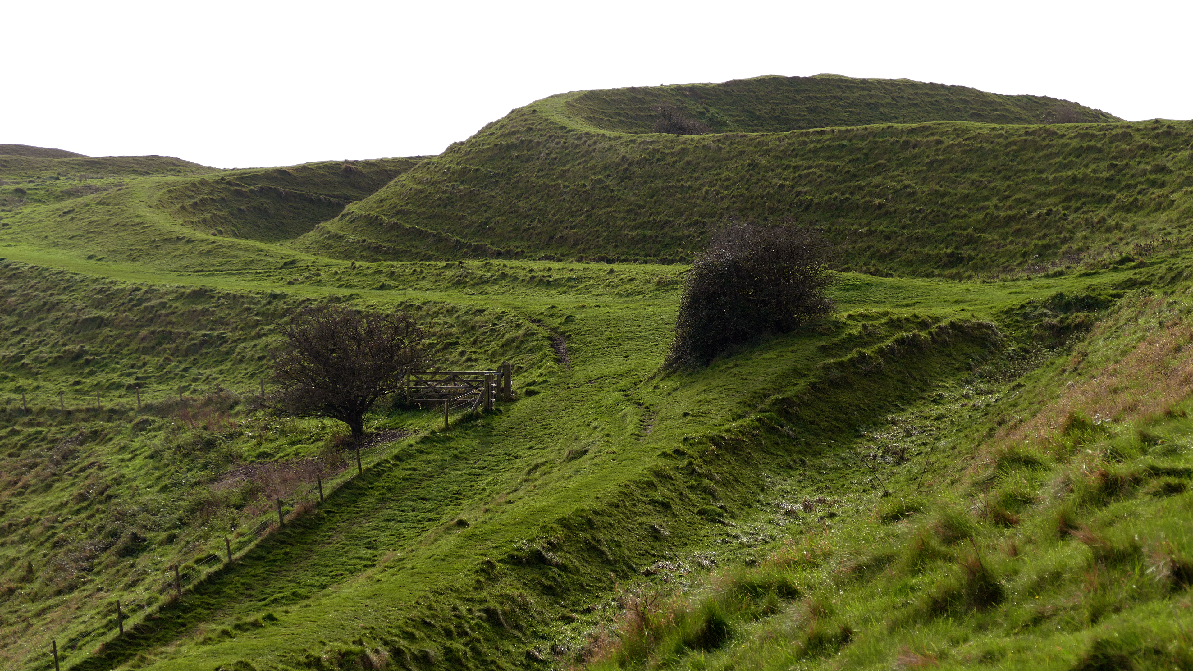 Photo of the remains of Iron Age Hill fort on a grassy hillside