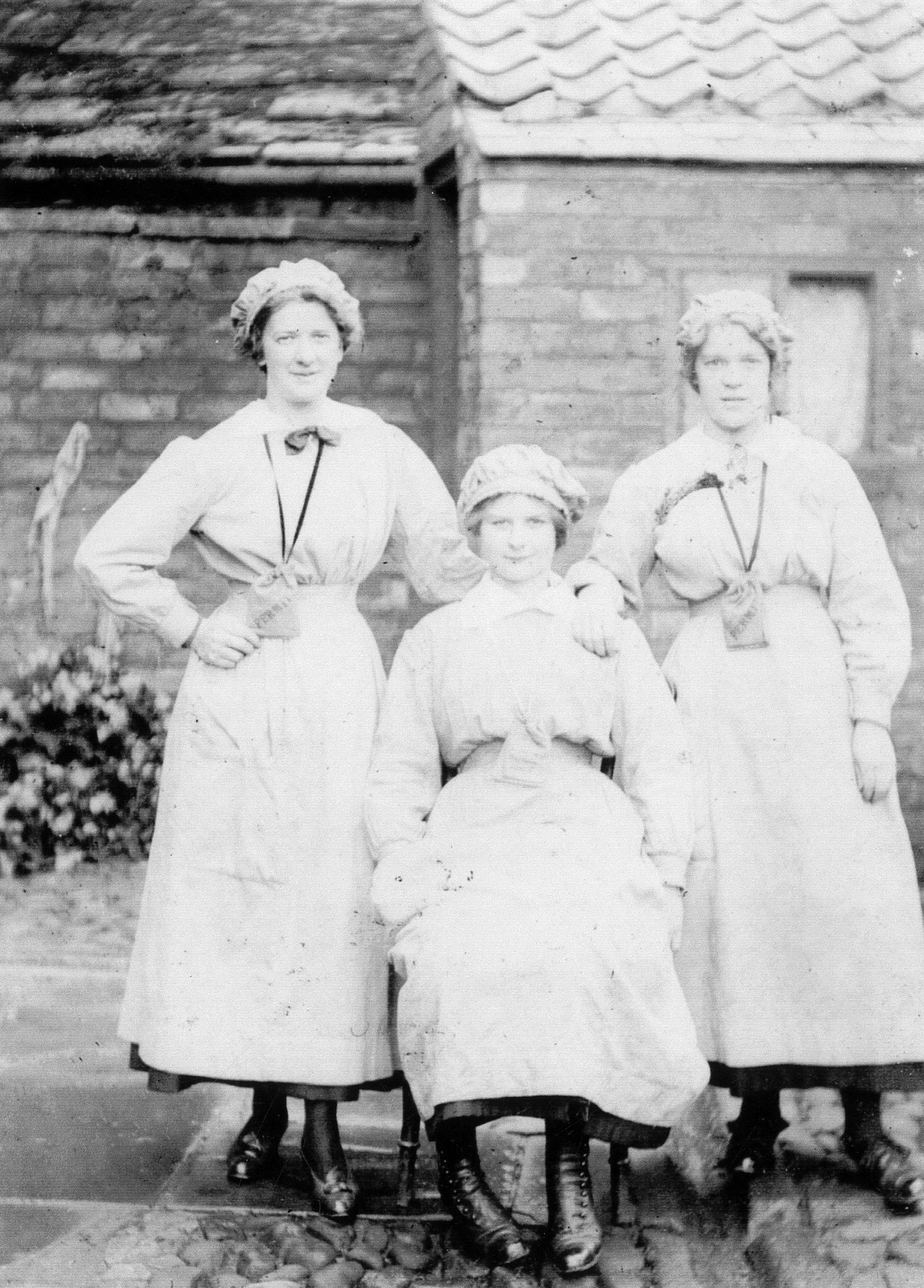 black and white portrait photograph of three young female munitions workers outside a building at Barnbow Munitions Factory