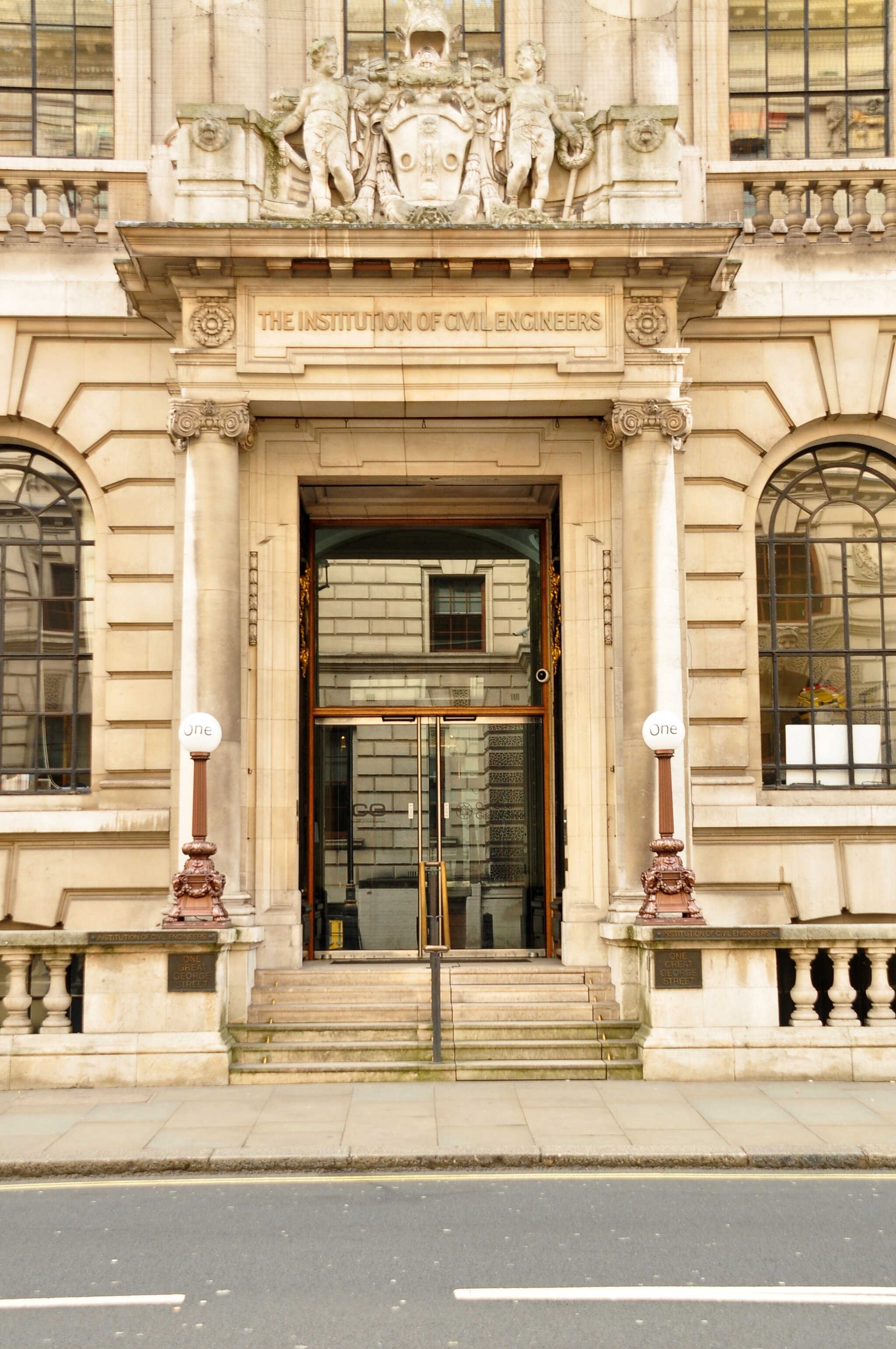 Photograph of the entrance to a building with steps and a large glass doors.