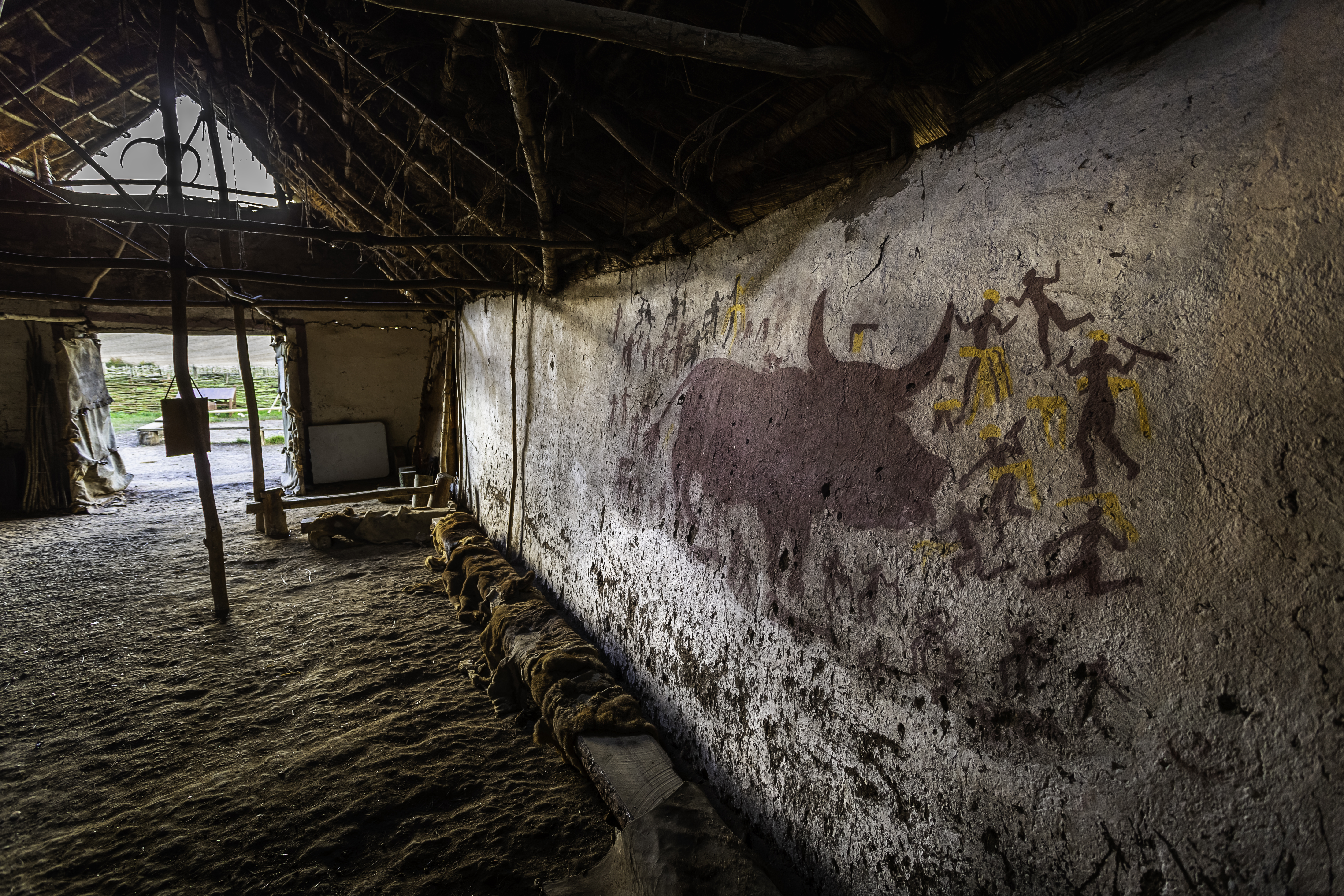 Stone Age Building Reconstruction Interior view showing wooden benches, animal skins and prehistoric wall painting