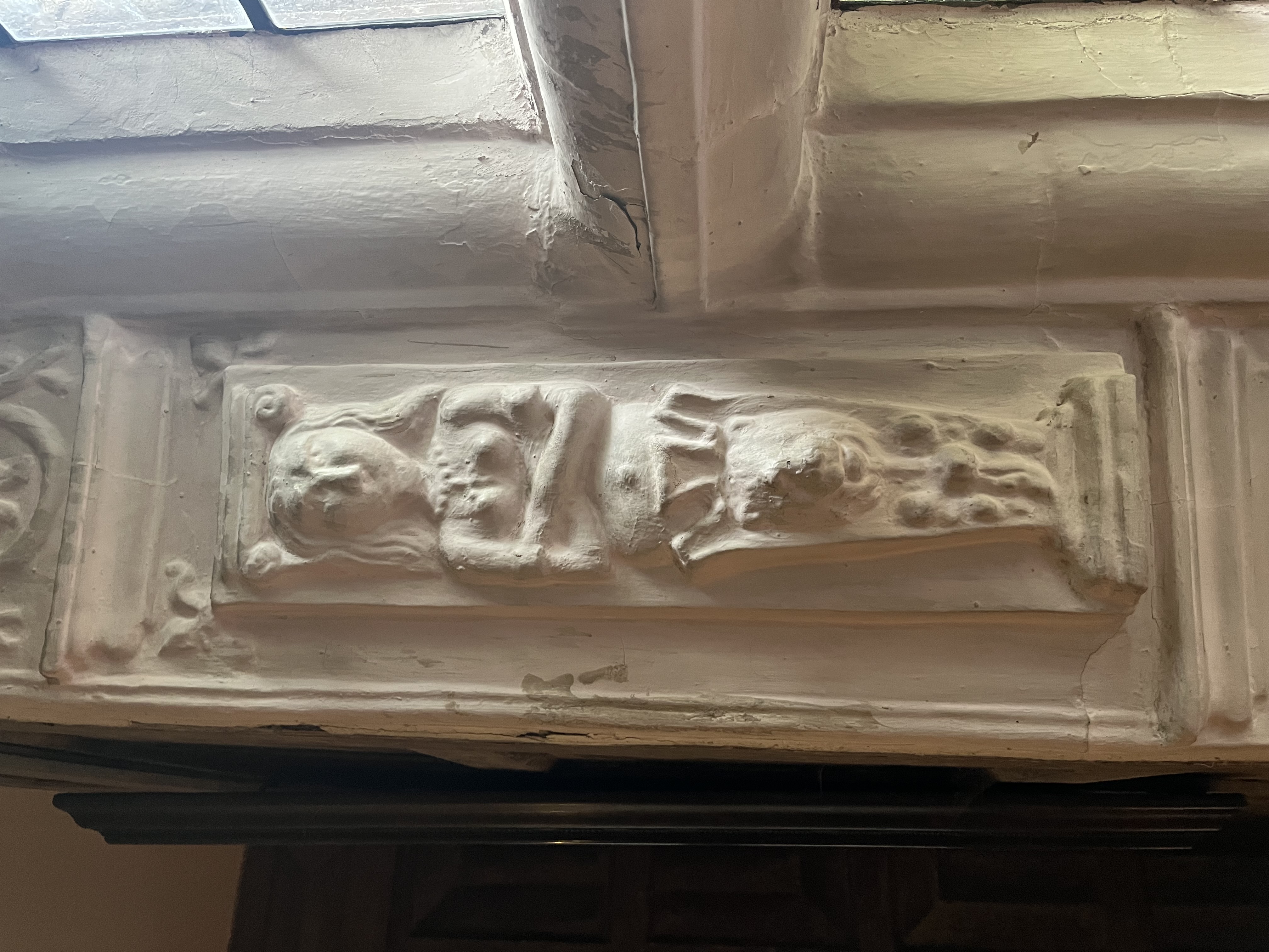 A colour photograph of a stone relief sculpture depicting a female figure with crossed arms, integrated into a window alcove.