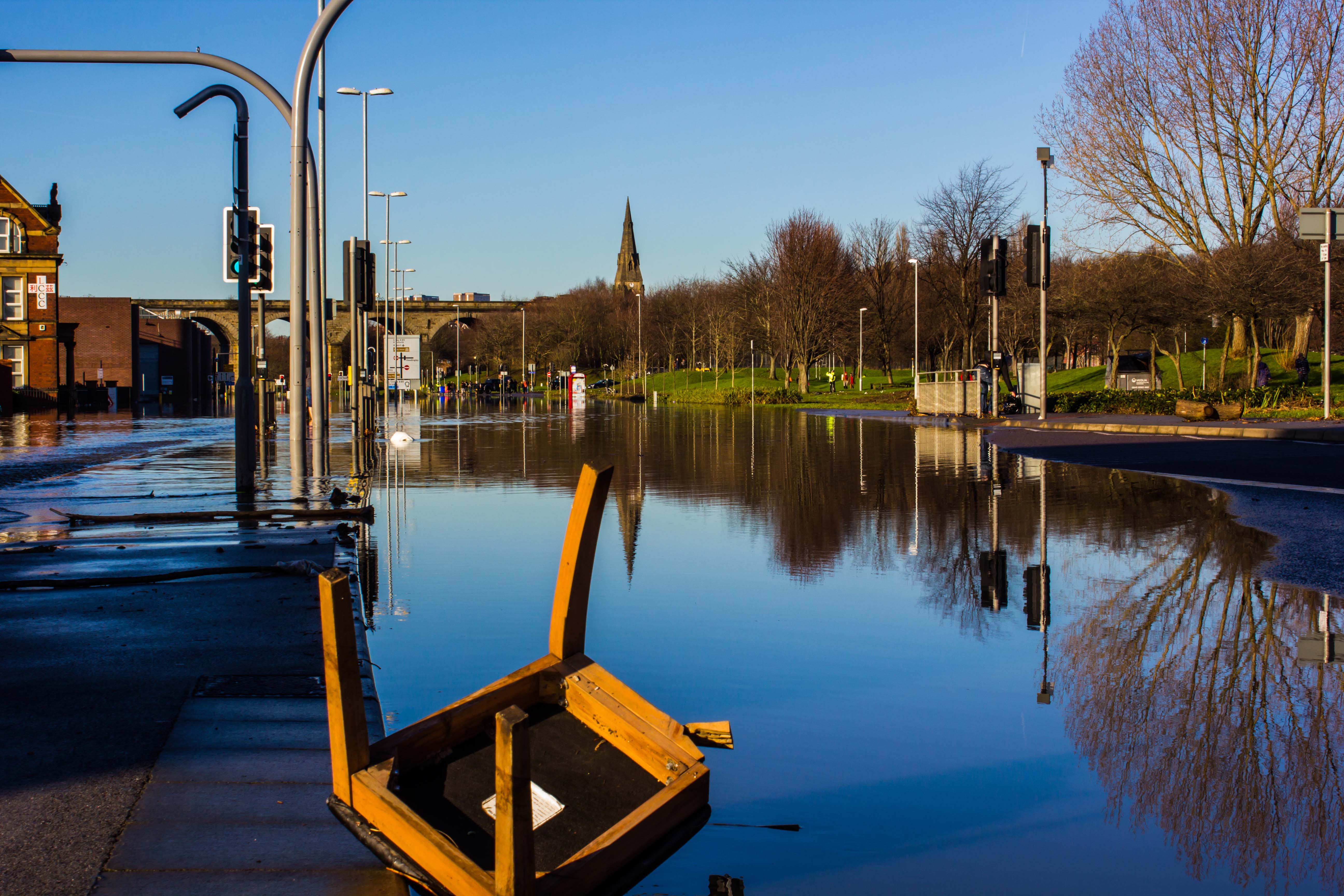 Colour photograph showing a major road underwater.  An upside down chair is floating in teh foreground.
