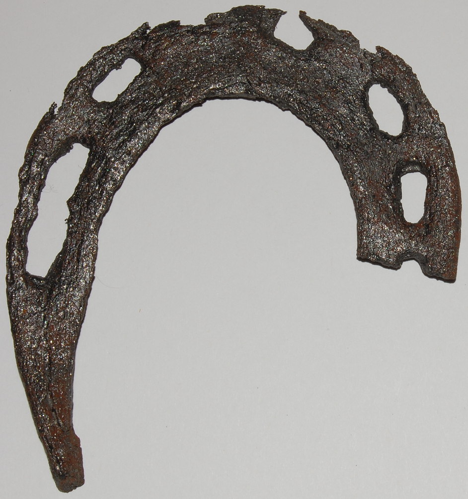 A rusted, worn-down horseshoe with several large holes against a plain background.