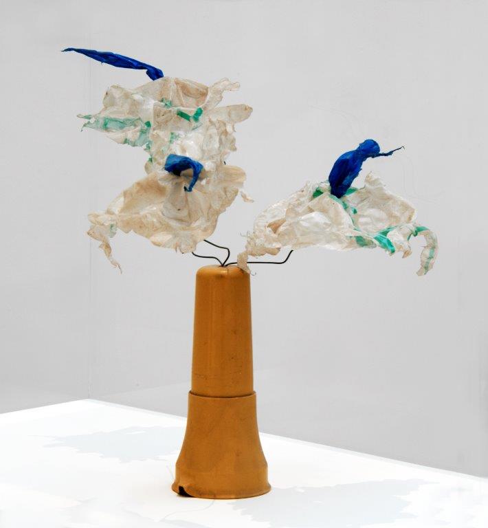 Colour photograph showing a sculpture of flowers in a vase, made from recycled plastics.