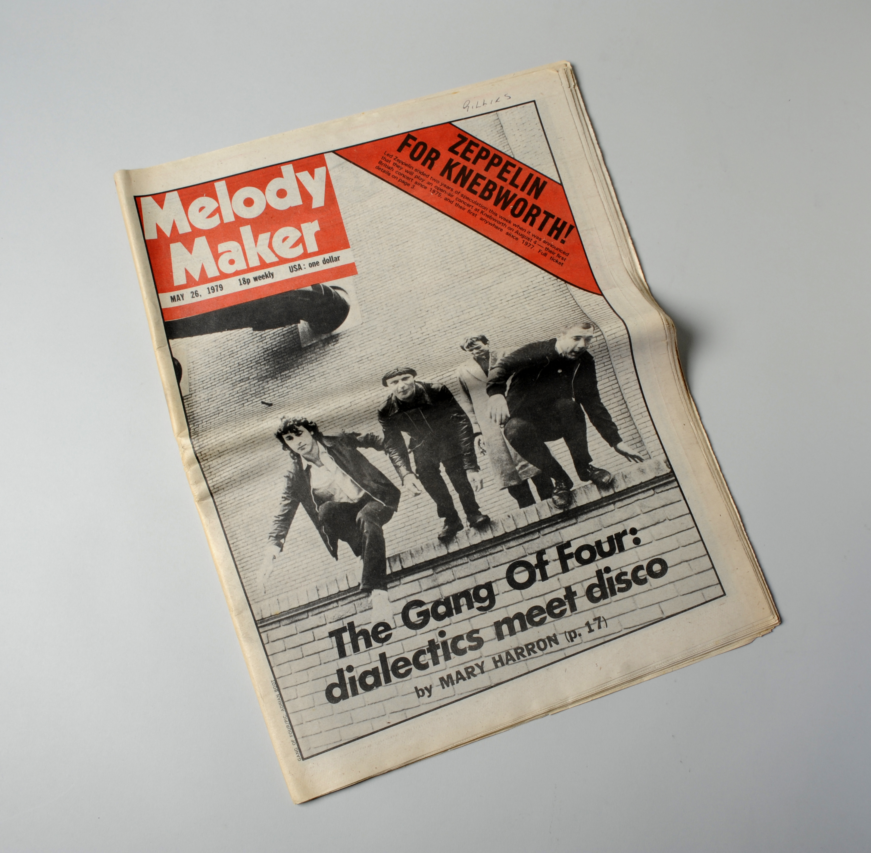A copy of a magazine with 'Melody Maker' written in white on a red background and a black and white photo of a band 'The Gang of Four' on the front.
