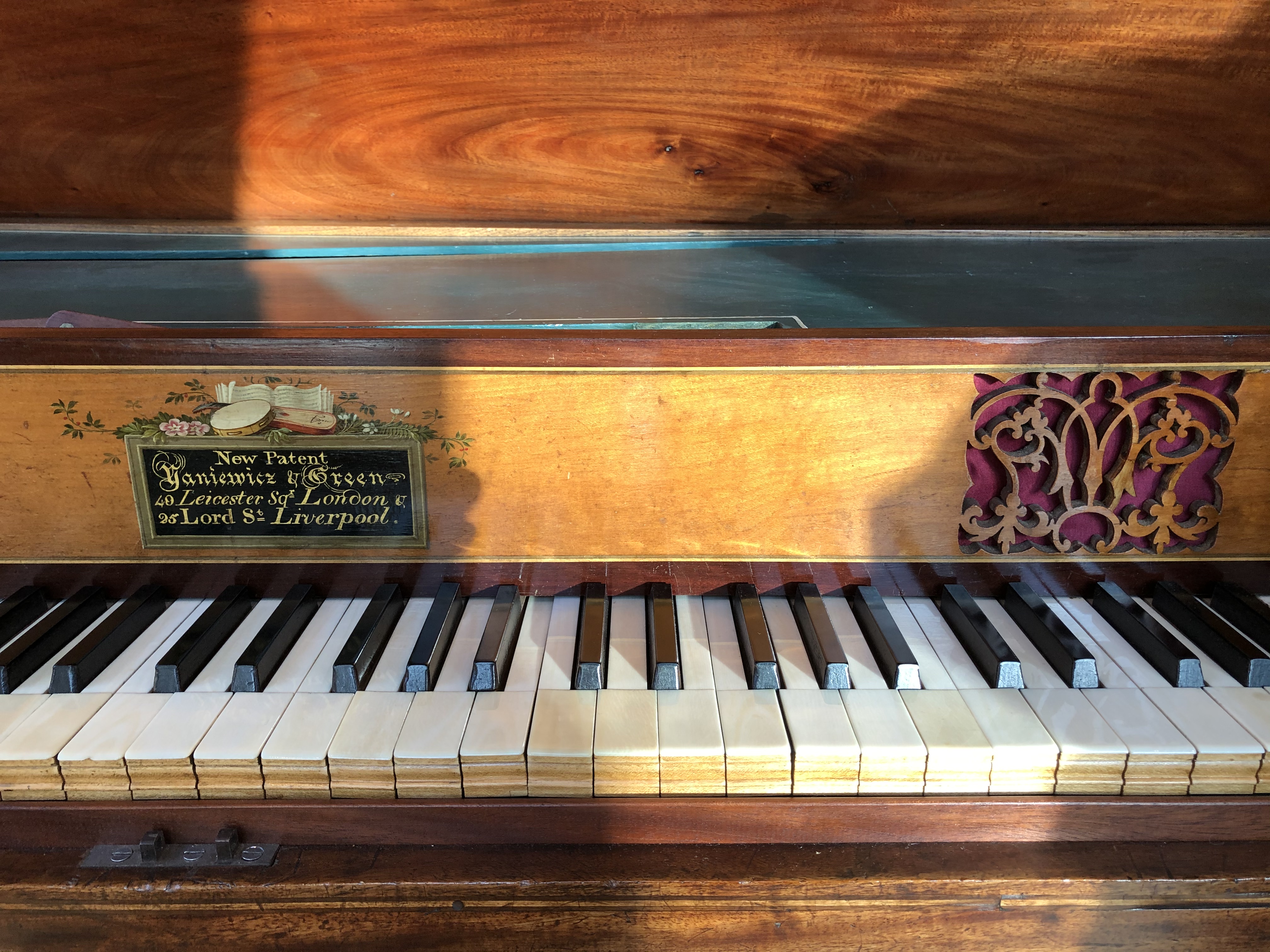 Yaniewicz and Green piano keyboard showing front of square piano including label and decorative wooden carving of fretwork
