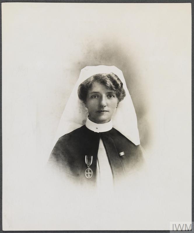 Sepia-toned portrait of a nurse in a uniform with a white cap, wearing a medal. The expression is calm and dignified. The background is soft.