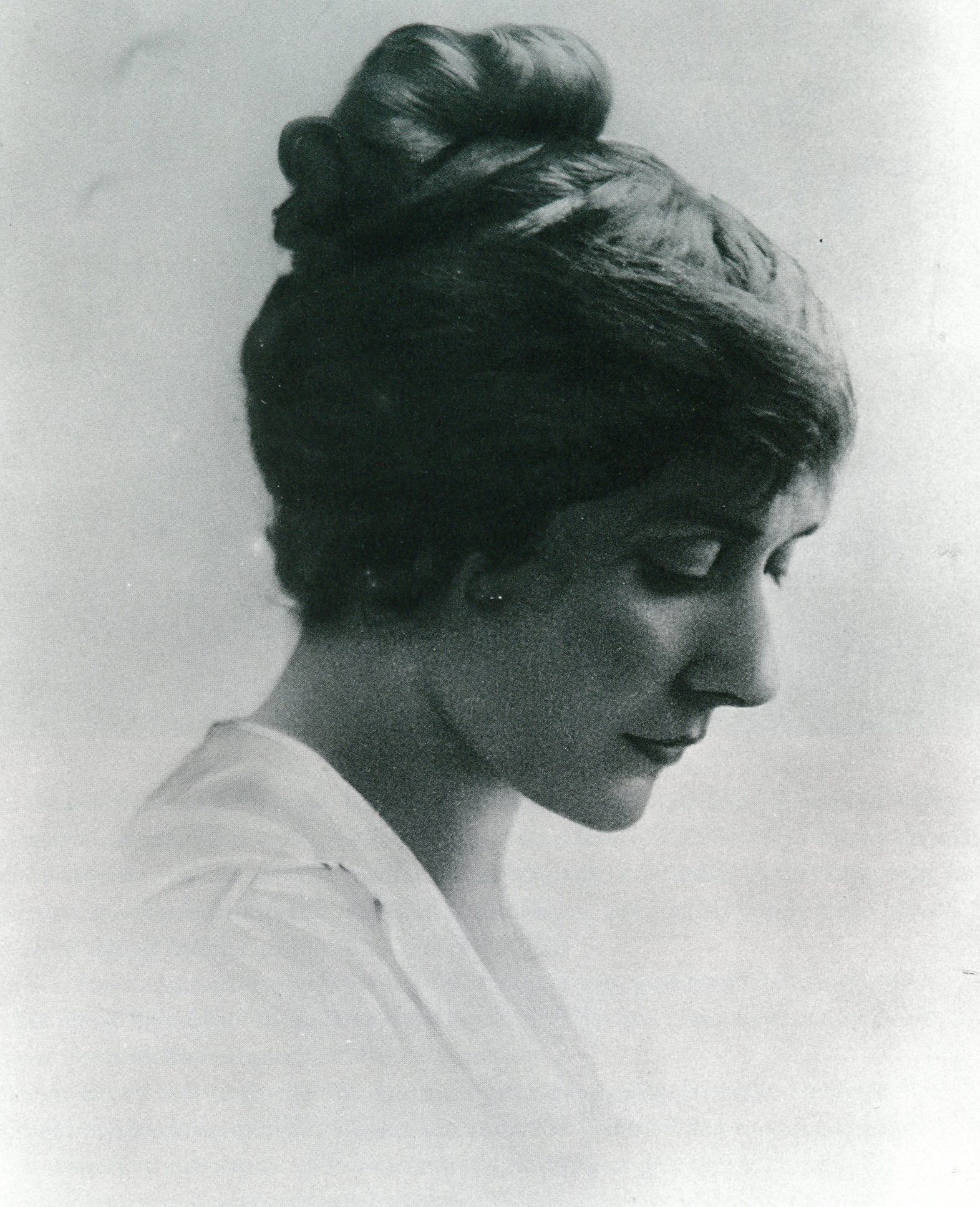 black and white portrait photo of young woman with hair in a bun looking downwards