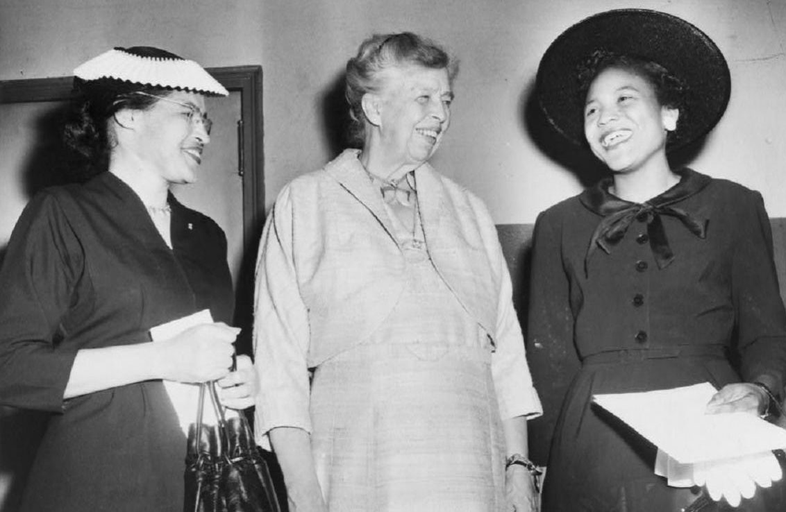 Black and white photograph showing three ladies standing together and smiling