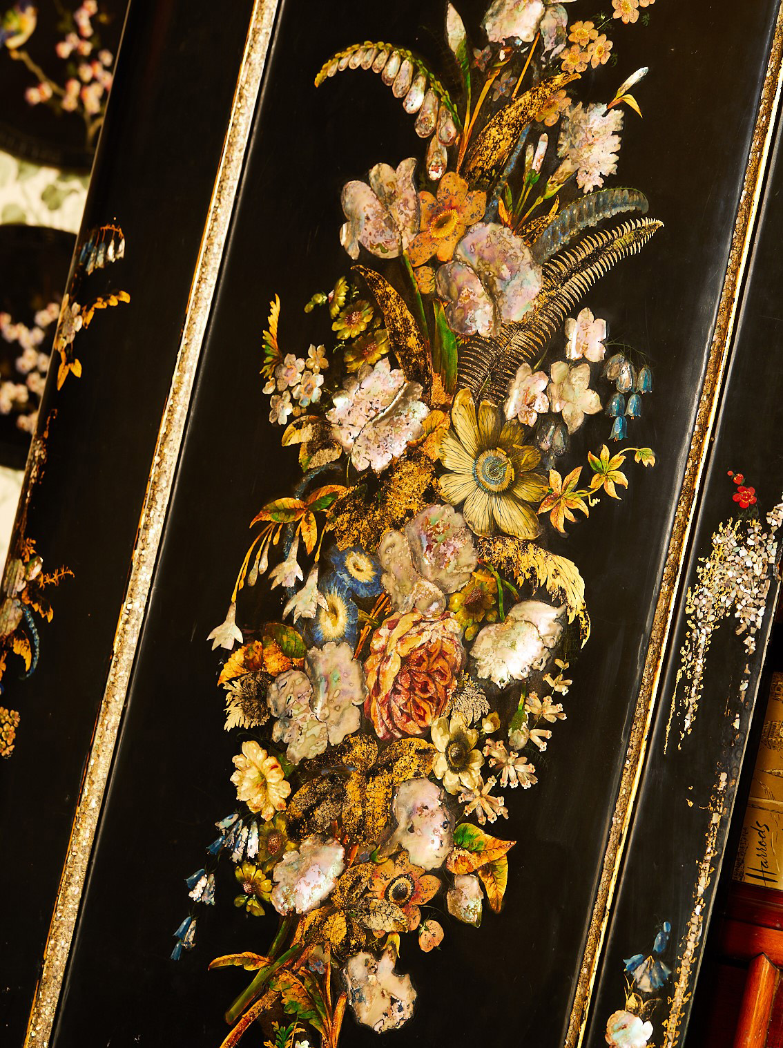 Close up showing painted flowers on a black papier mache background