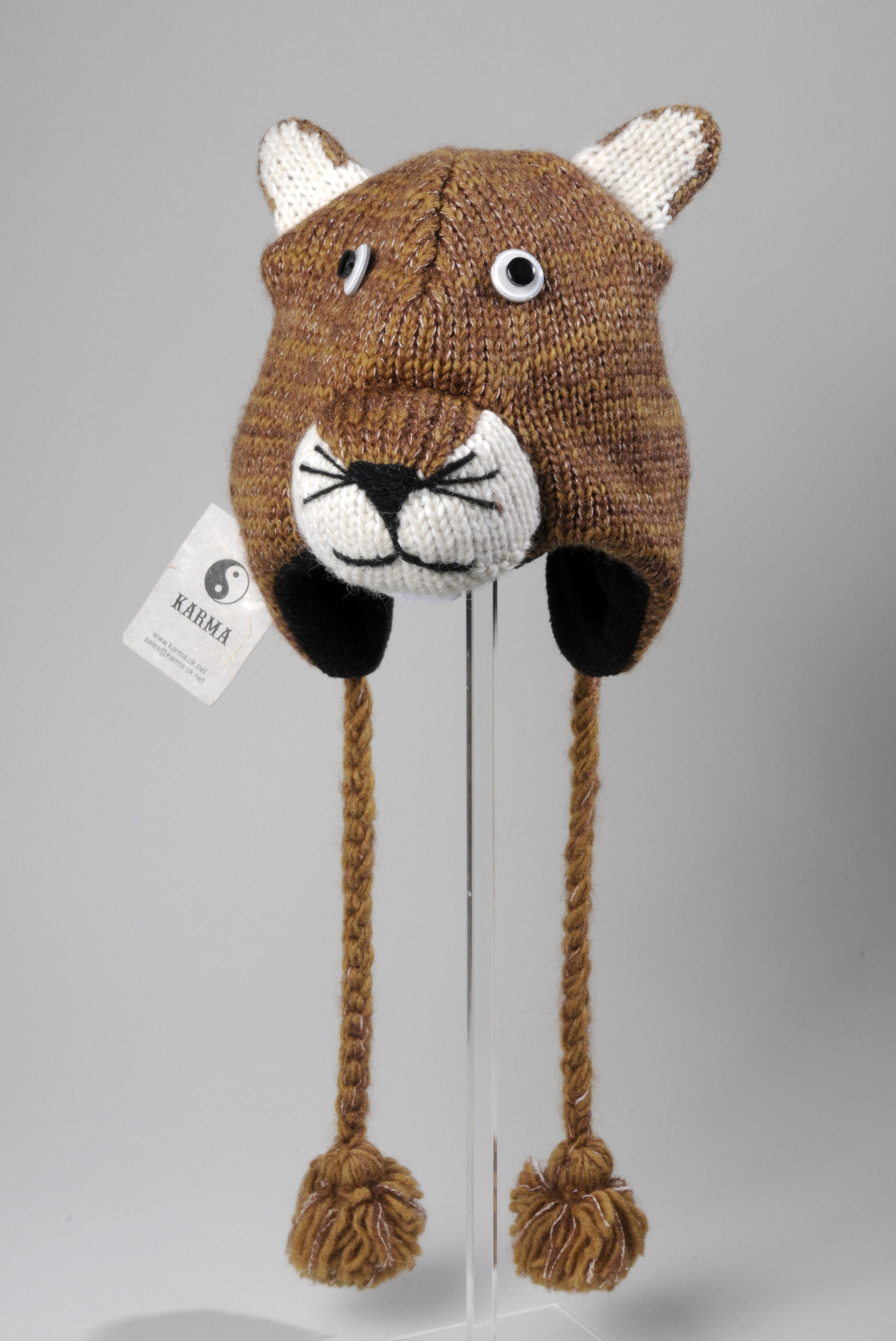 Knitted hat in the shape of a bear face, with pointy ears and  long tassels with pom-poms on the end.