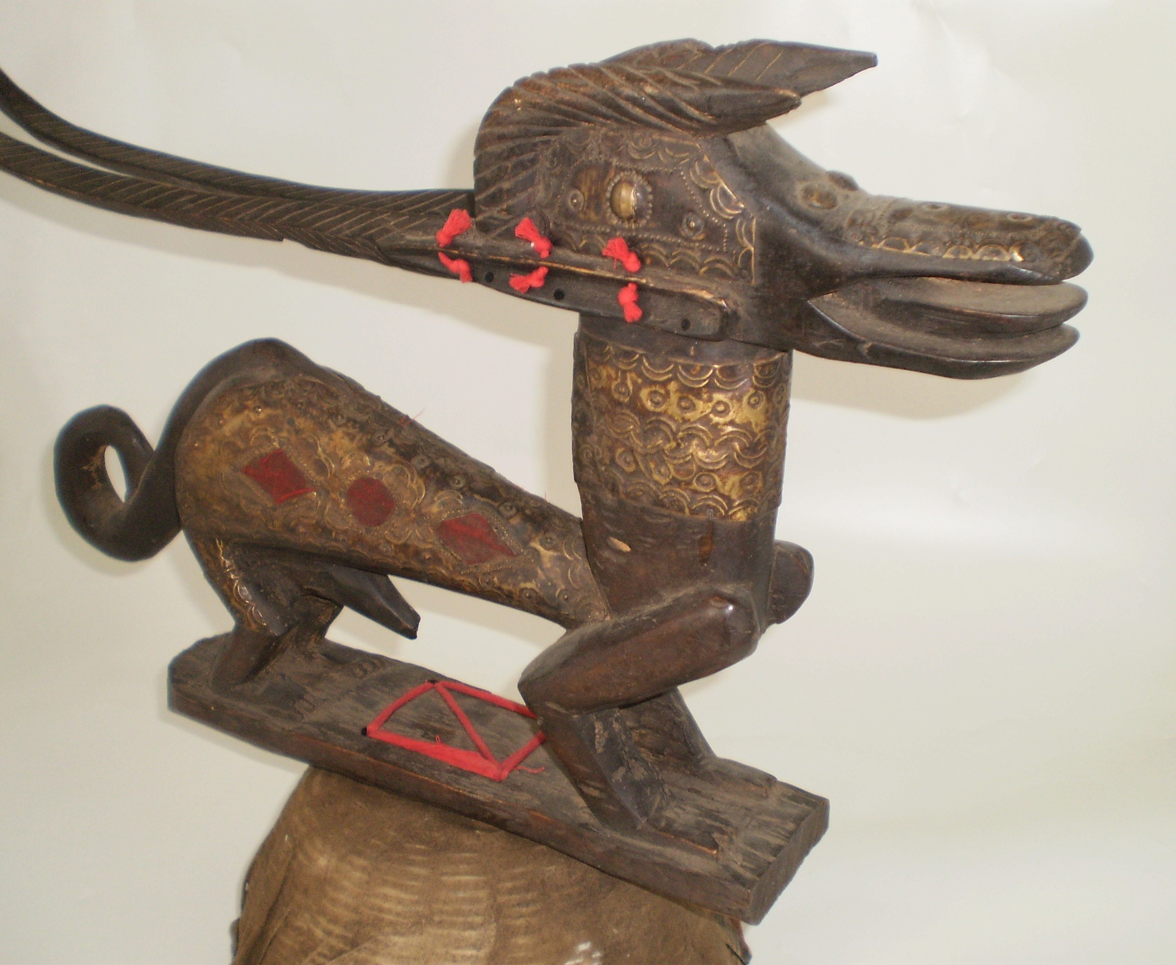 Wooden carved dog with a woven base that can be worn on the head.