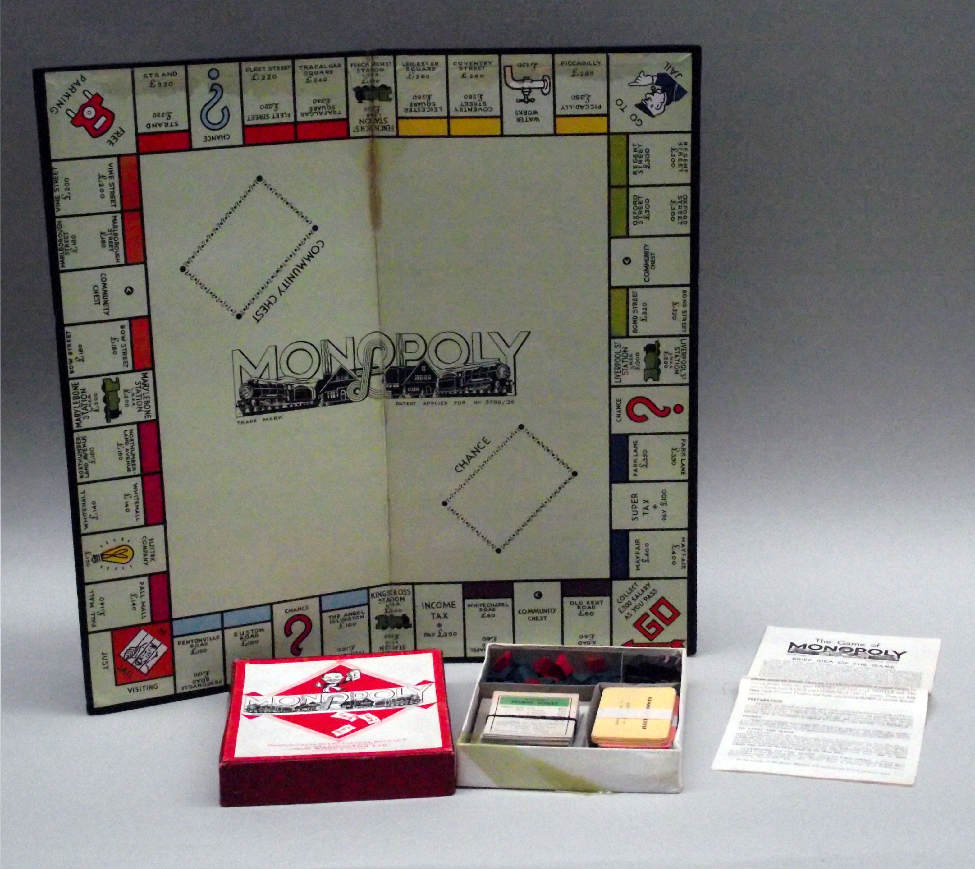 Colour photograph of a Monopoly board showing a smaller box with the cards and houses and hotels