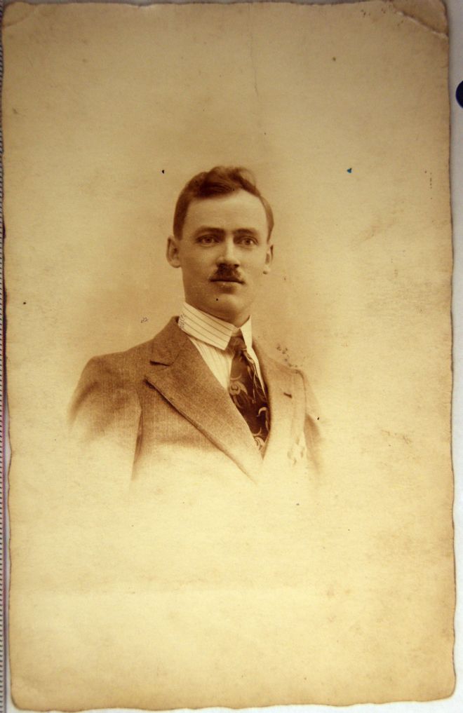 Studio portrait photograph of Cryrille.  He is wearing a suit and tie and has a moustache