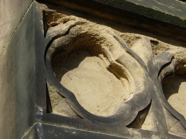 Photograph of a carved area on the outside of a building.  Part of the carving has weathered away .