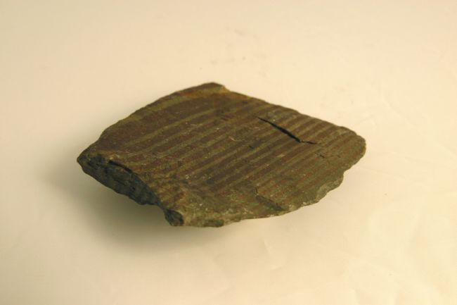 Banded rock made from horzontal stripes of darker and lighter material.