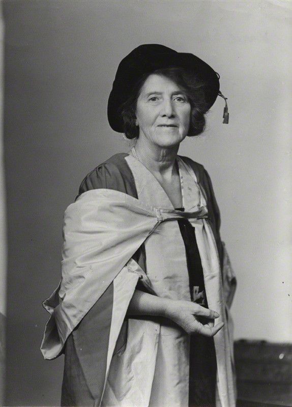 Black and white photograph. Marie Stopes is wearing a floppy hat (from when she received her doctorate) and an academic gown.